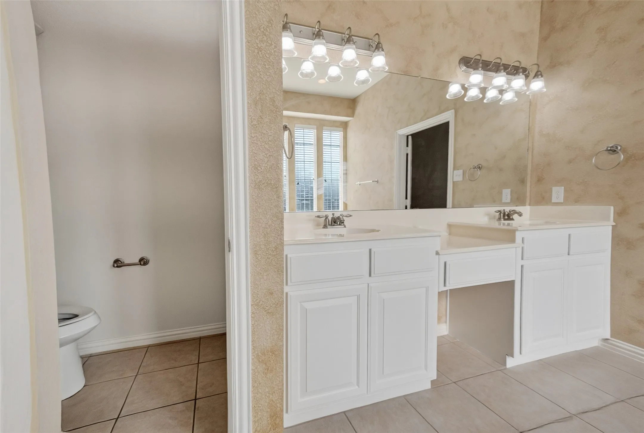 Dual vanity with white cabinetry, integrated sinks, chrome fixtures, and a large wall-mounted mirror