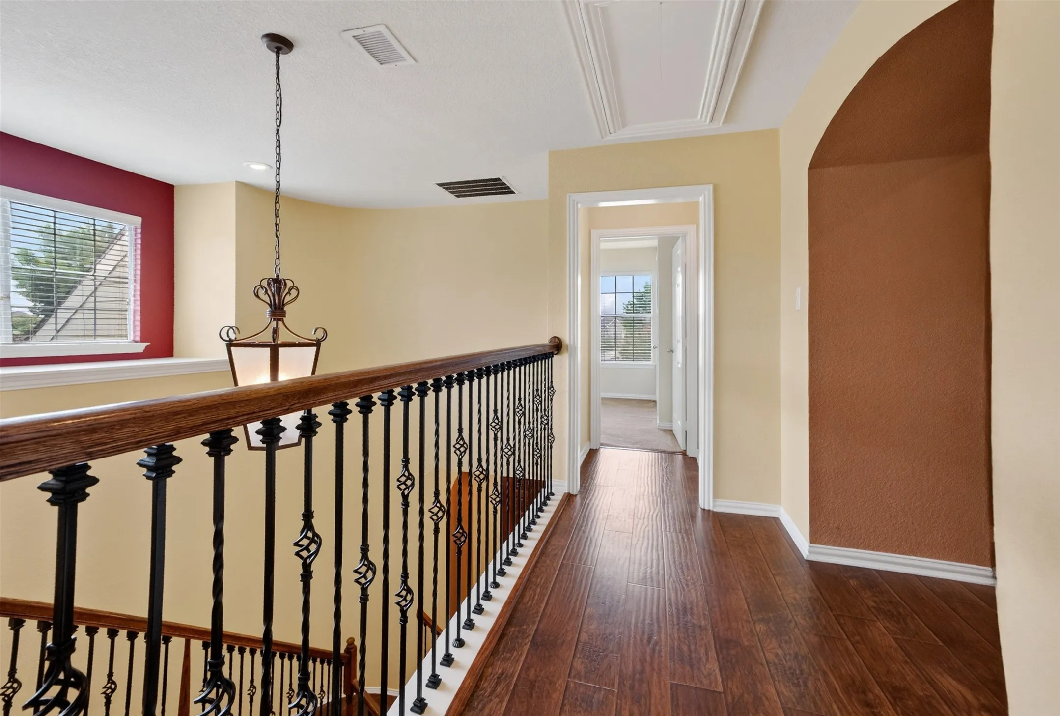 Upper-level landing featuring wood-finish flooring and an ornate wrought-iron and wood handrail