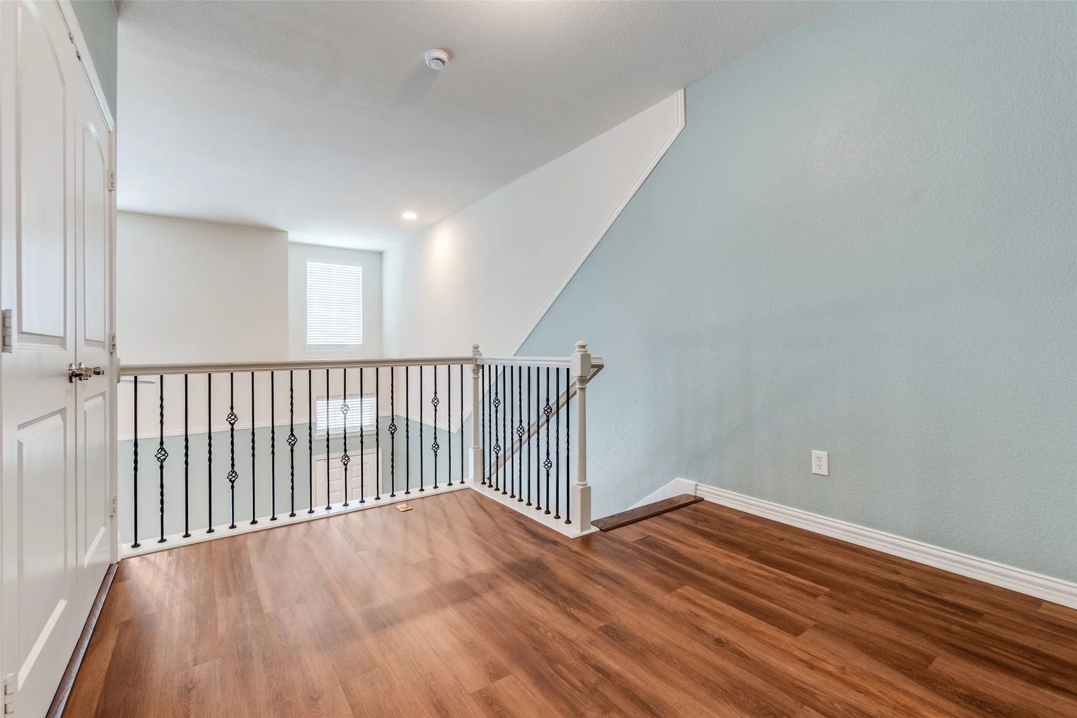Empty room with wood finished floors, baseboards, and a smoke detector