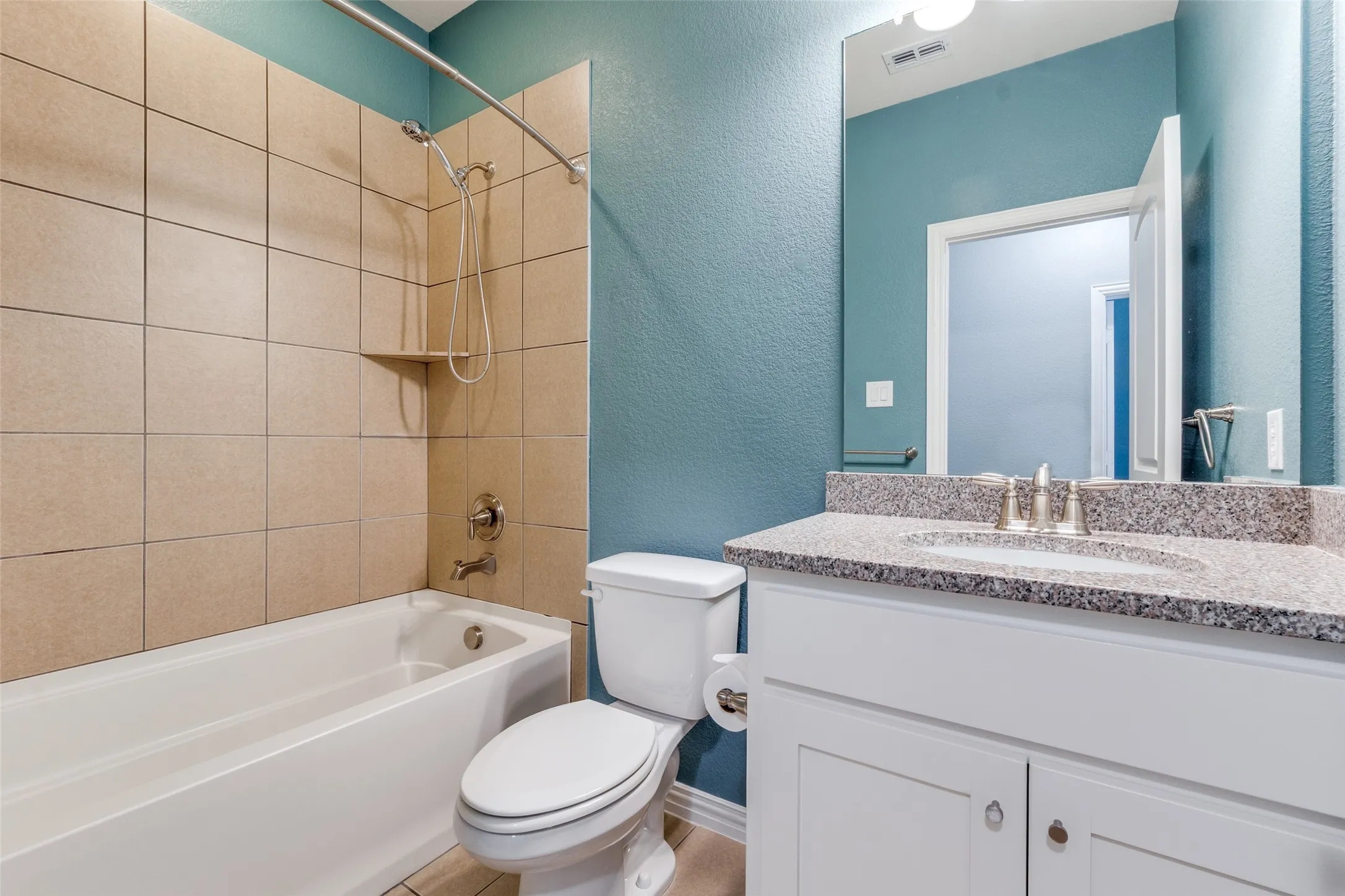 Full bathroom with a textured wall, toilet, shower / washtub combination, and vanity