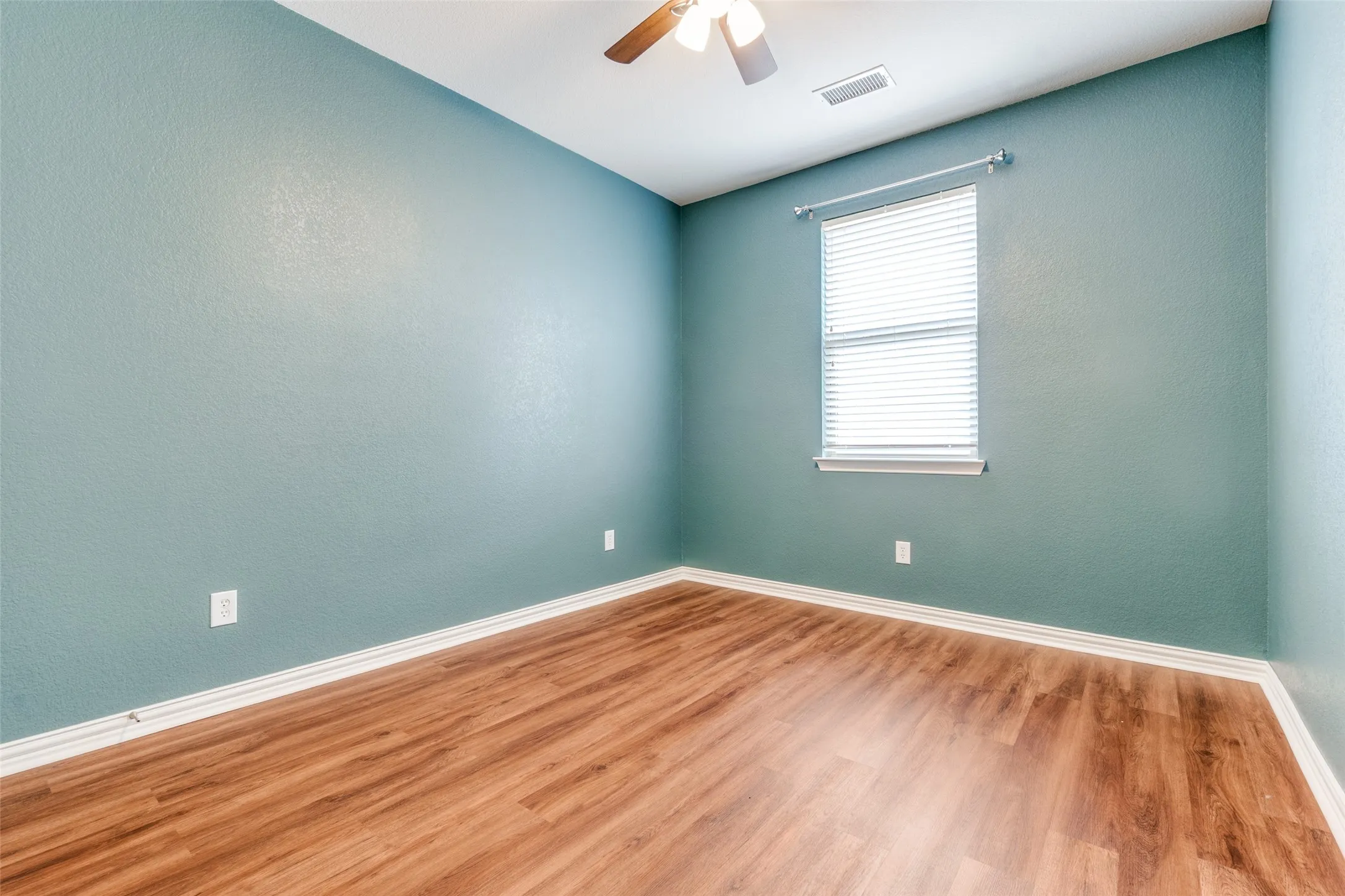 Empty room featuring baseboards, wood finished floors, and a ceiling fan