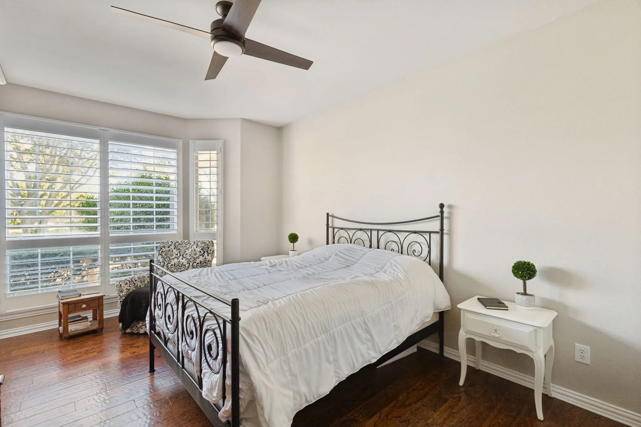 Split secondary bedroom on the first floor makes for a perfect guest room. The room boasts hardwood flooring, walk-in closet, plantation shutters and a ceiling fan.
