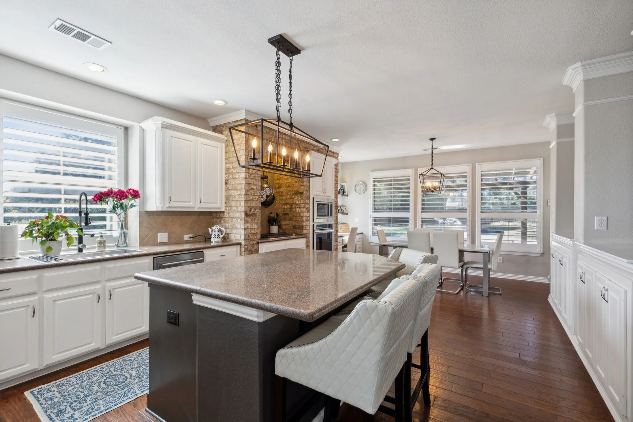This kitchen is a dream! Abundant granite counter space including the oversized island, great storage and white cabinetry are the beginnings of a wonderful kitchen! The space is bathed in natural light from the window over the sink to the wall of windows in the nook. Plantation shutters provide privacy when needed.