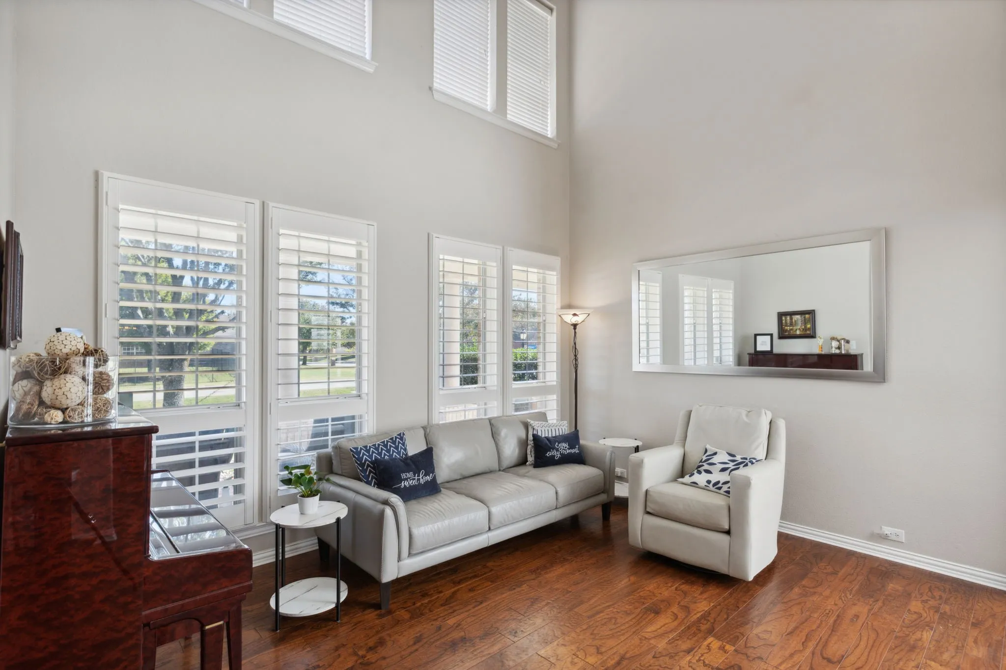 Formal living room enjoys ceilings that reach to the second floor, plantation shutters and double stacked windows to make this space so light and bright!