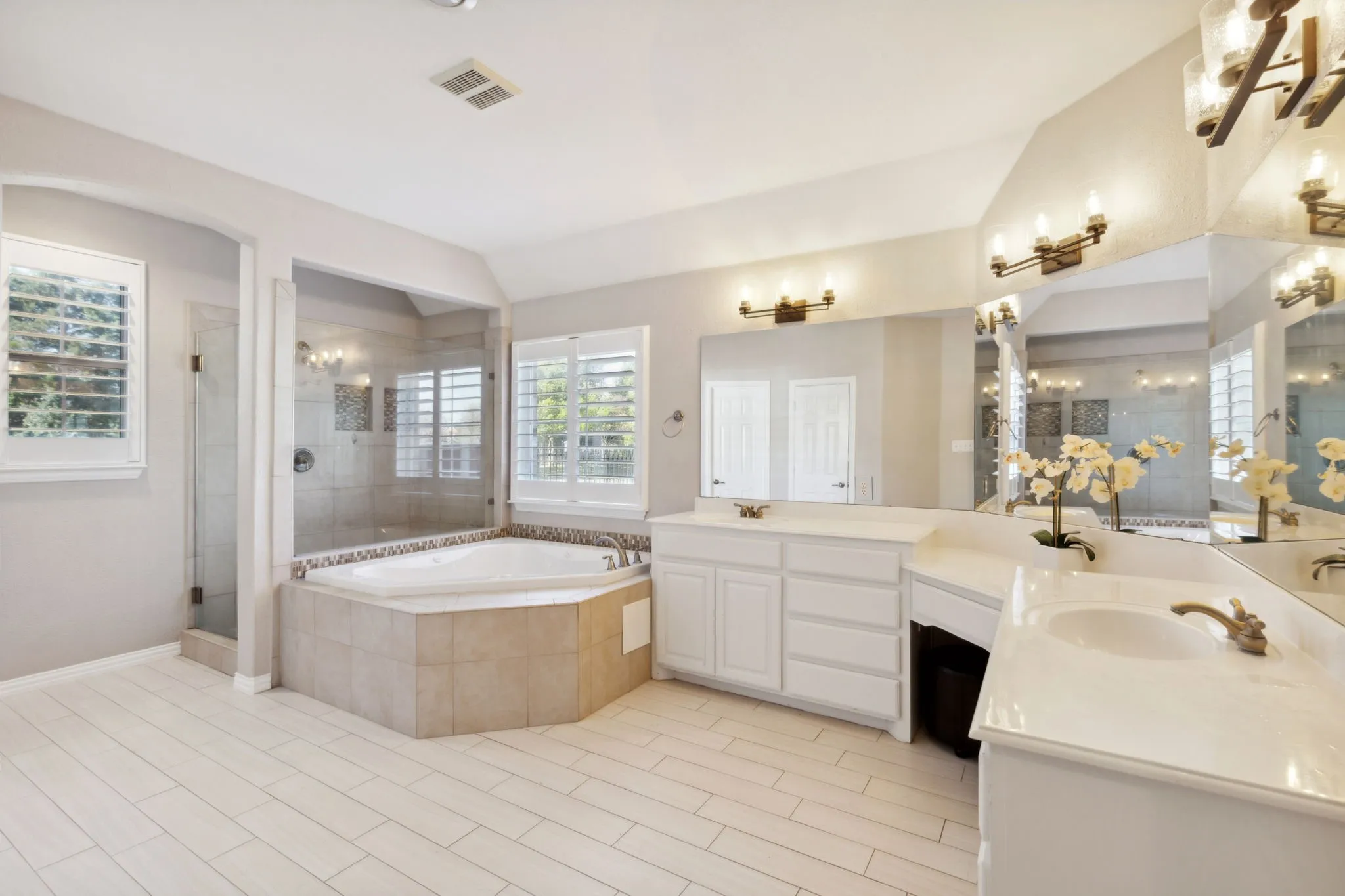 The spacious spa-like primary bathroom offers expansive vanity space with dual sinks, great storage and a wall of mirrors. Separate walk in shower and jetted tub are quite luxurious. Enjoy natural light through the plantation shutter covered windows.