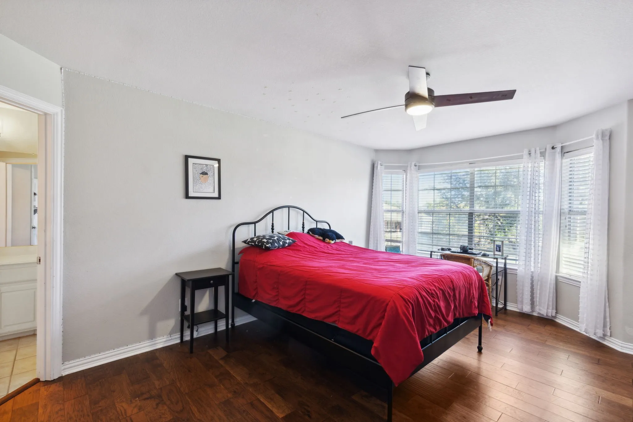 Split secondary bedroom with walk-in closet, ceiling fan, wood flooring and en suite bathroom that also opens to the hallway.