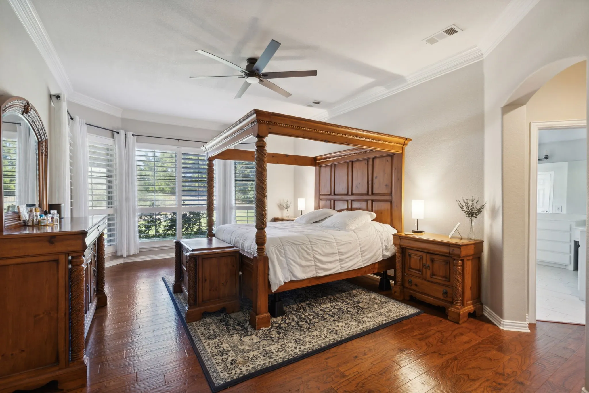 The primary bedroom offers handscraped hardwood flooring, crown moulding and updated ceiling fan. The bay window gives space for a sitting area and wonderful views of the backyard. Windows are graced with plantation shutters.