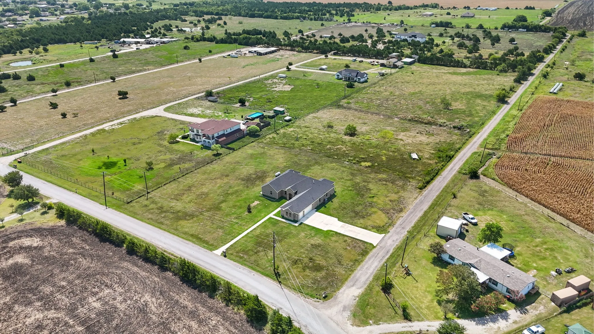 Aerial perspective showcasing a property with a paved driveway and an expansive surrounding landscape