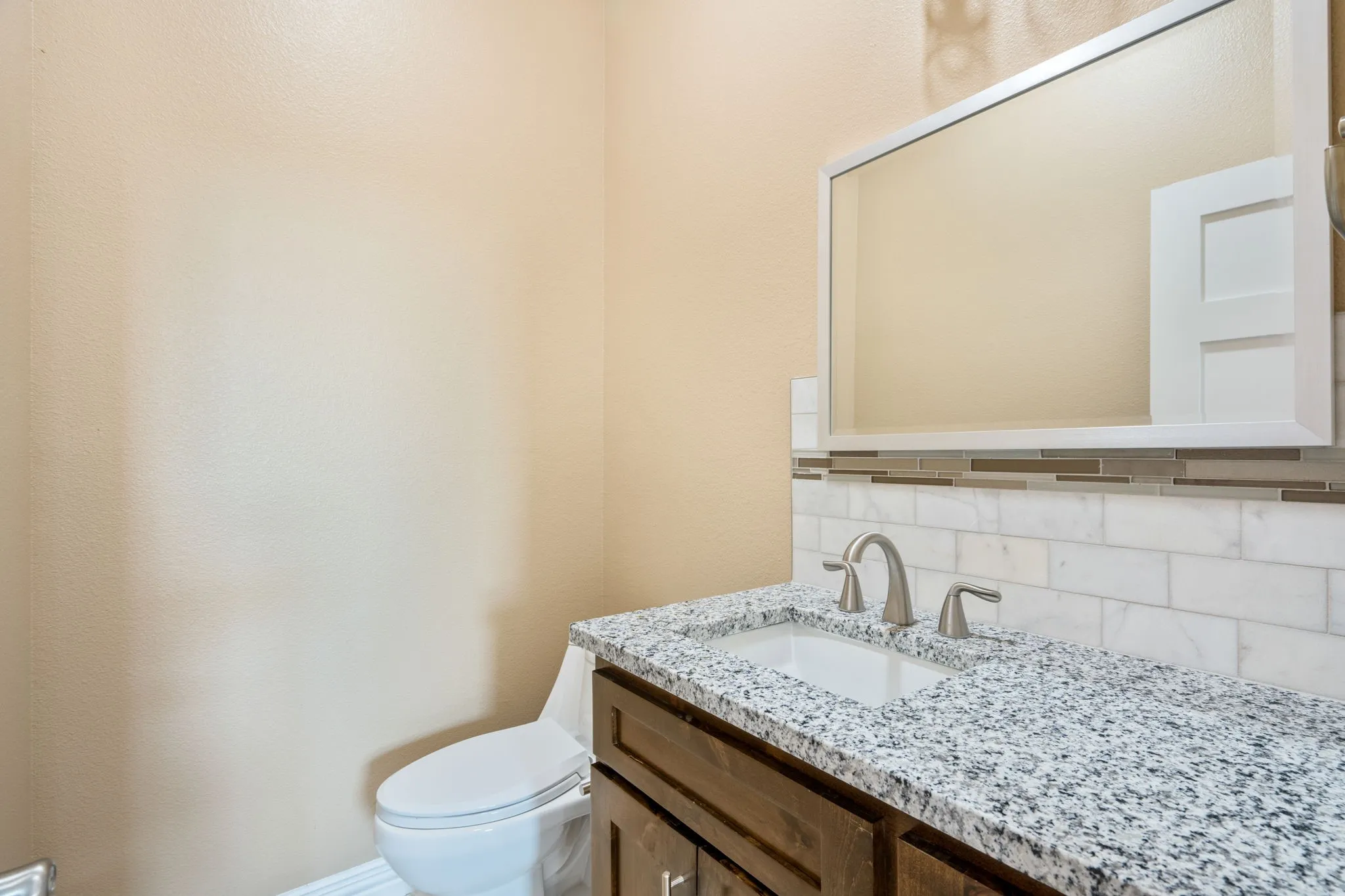 Bathroom vanity featuring a speckled countertop, undermount sink, and brushed nickel faucet