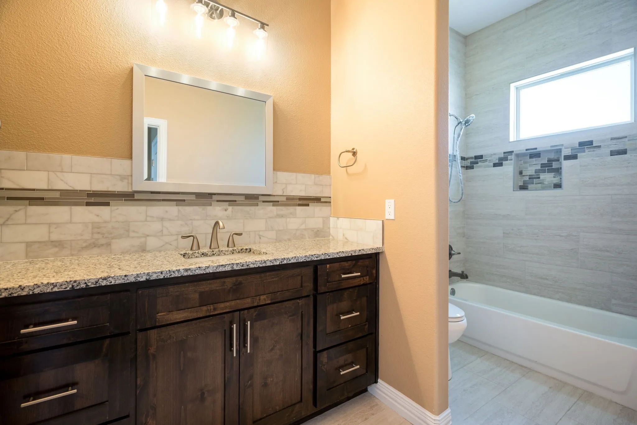 Vanity with dark wood-finish cabinetry, light-toned granite countertop, and undermount sink