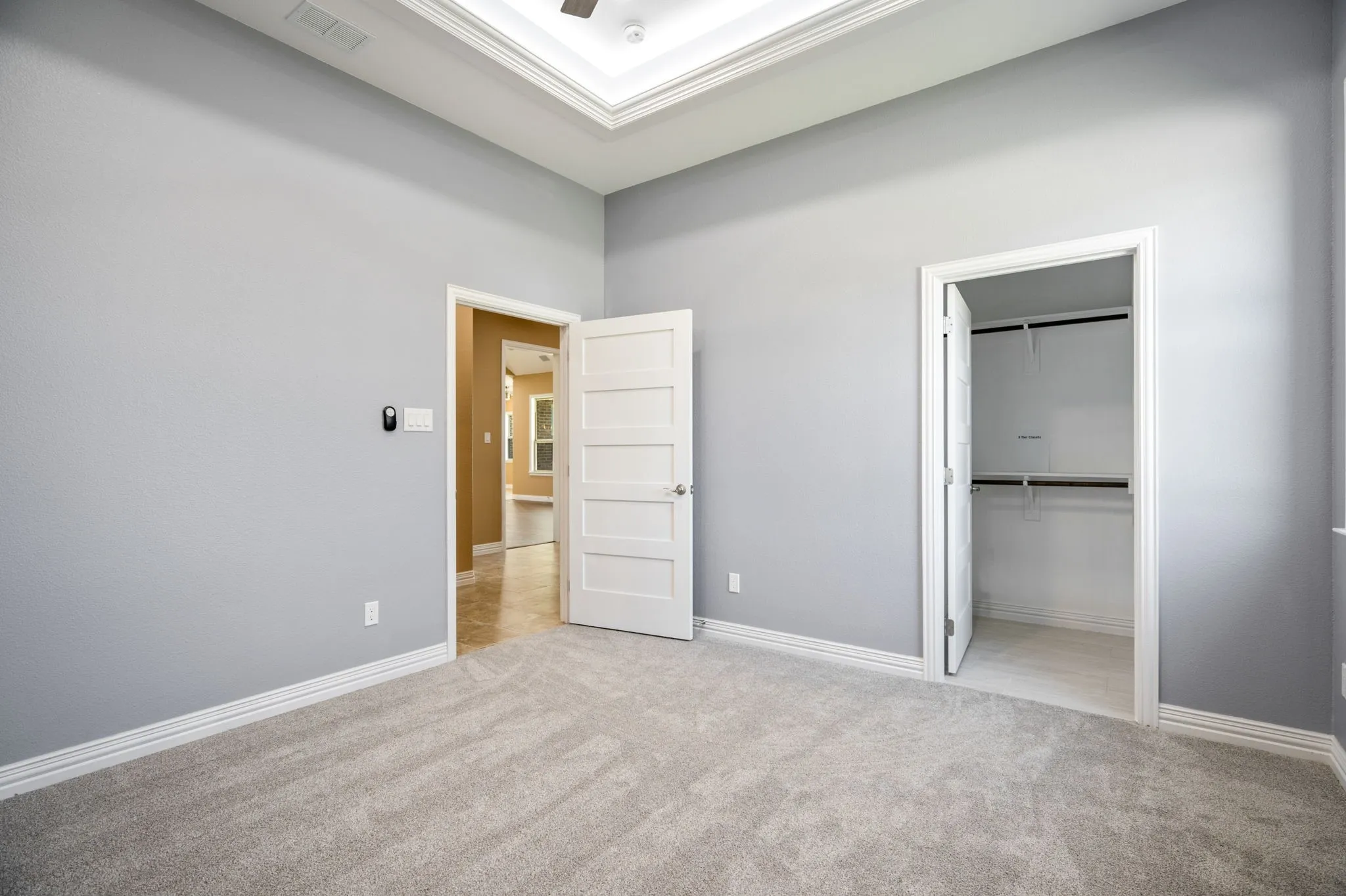 Carpeted room with a tray ceiling and a ceiling fan