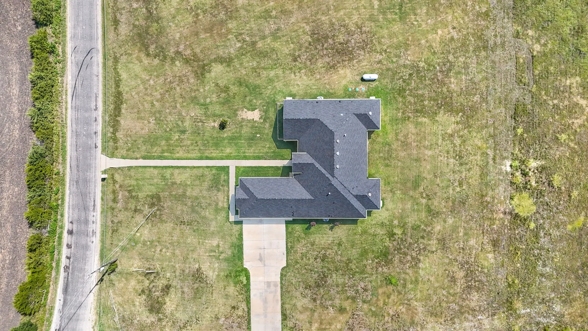 Aerial overview showcasing a property with a dark shingle roof and a concrete driveway