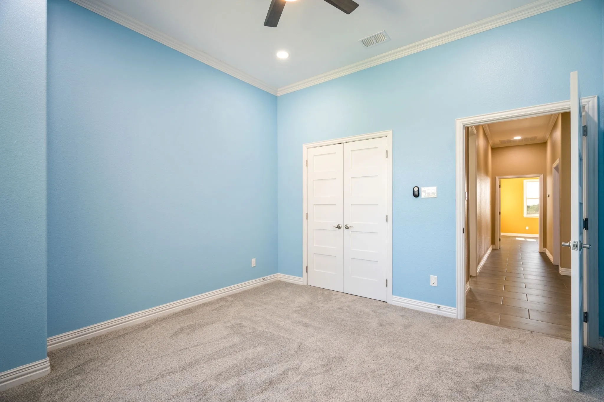 Room featuring light blue walls, light gray carpet, and white crown molding