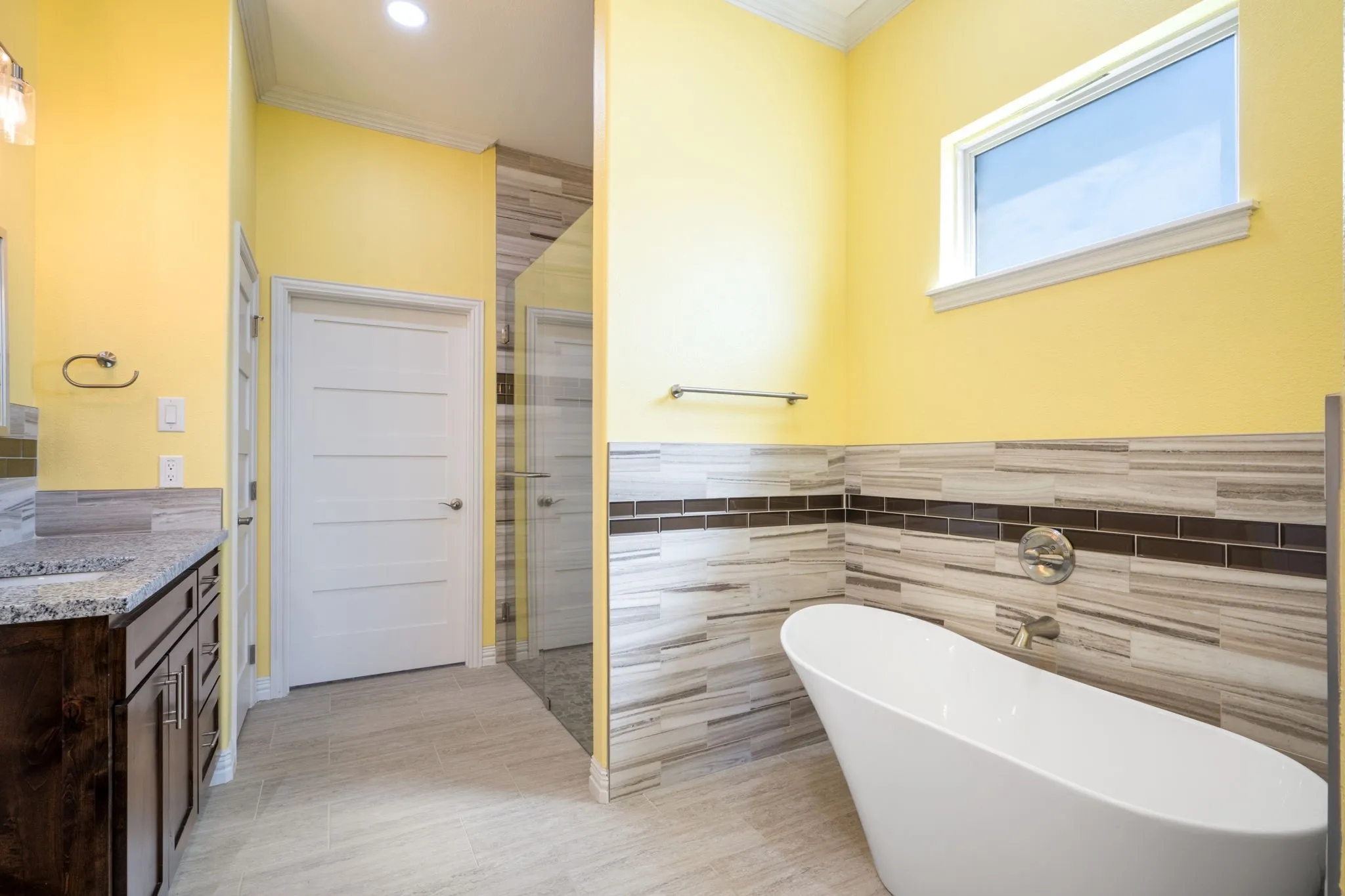 Contemporary bathroom featuring a freestanding soaking tub, glass-enclosed shower, and a dual-sink vanity with a granite countertop