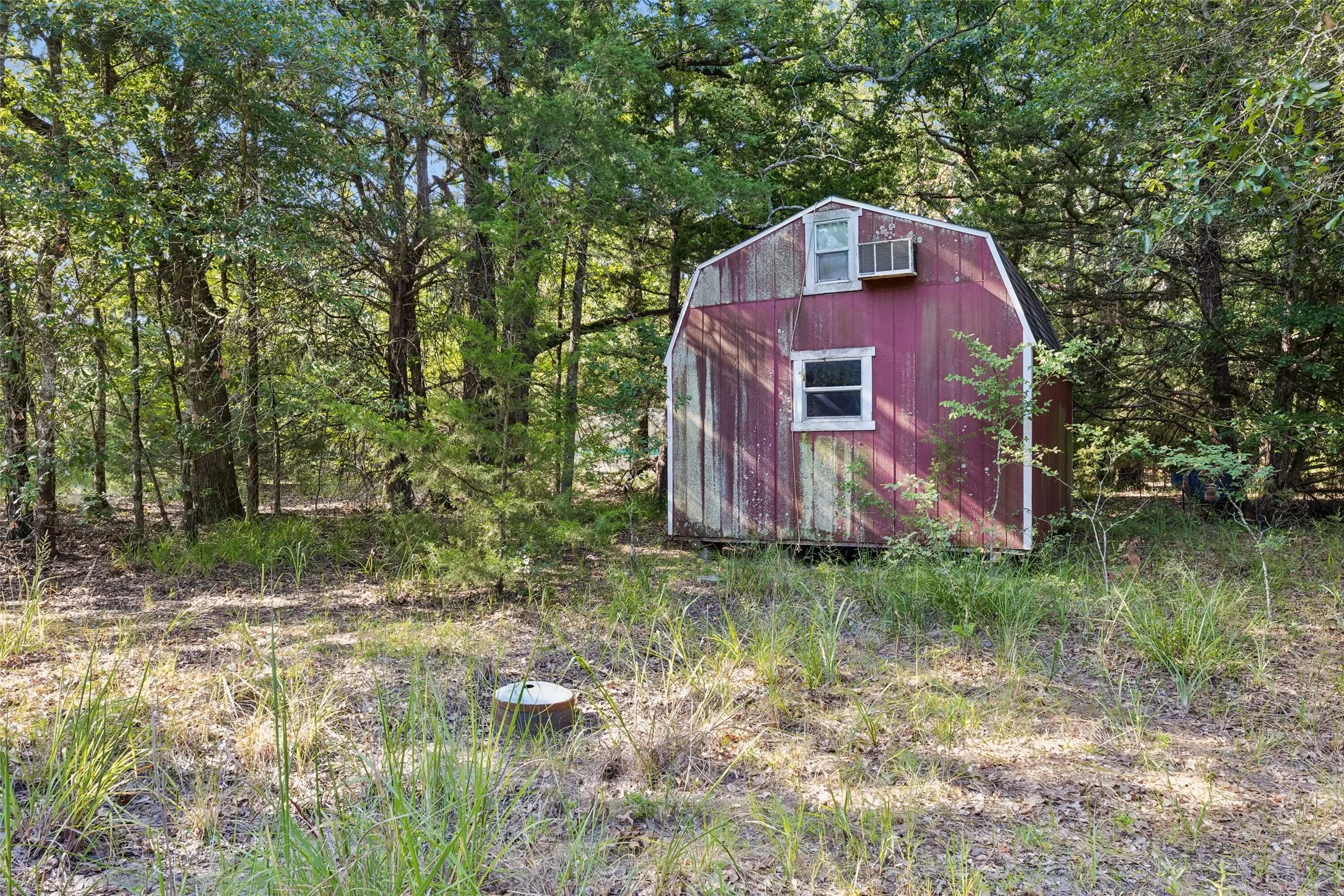 Red-sided shed featuring a gambrel roof, white-trimmed window