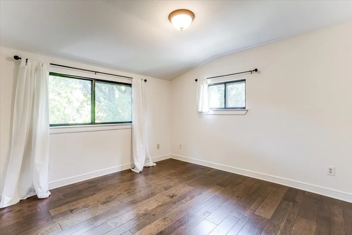 Room featuring wood-finish flooring, white walls, and white baseboards