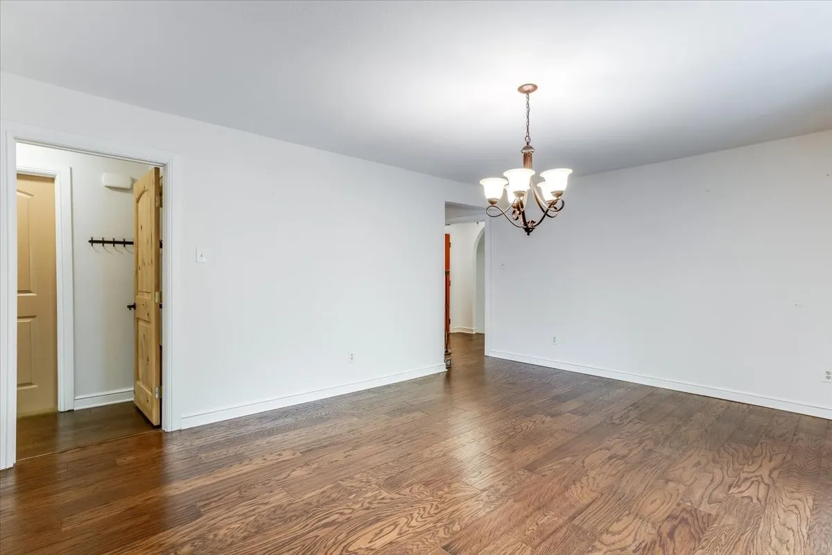 Spacious interior featuring wood-finish flooring, white walls, and a traditional chandelier