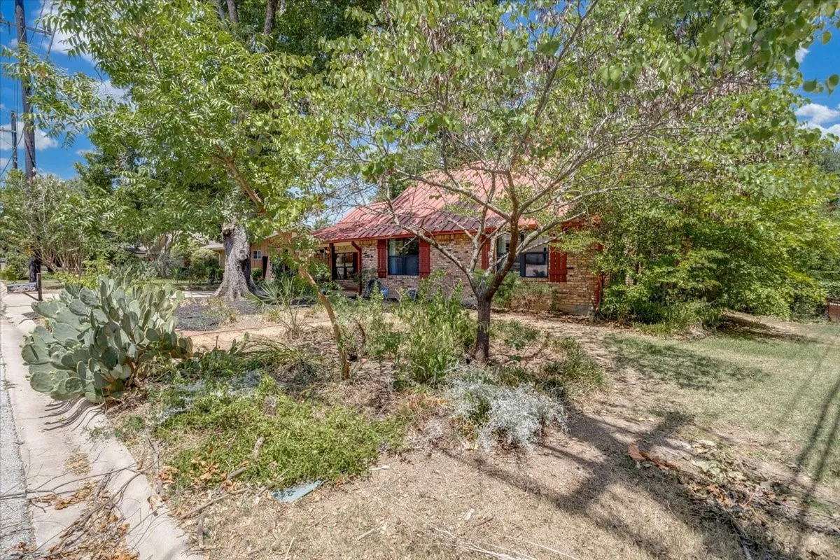 Exterior features a red tile roof, brick facade, and dark framed windows with red shutters