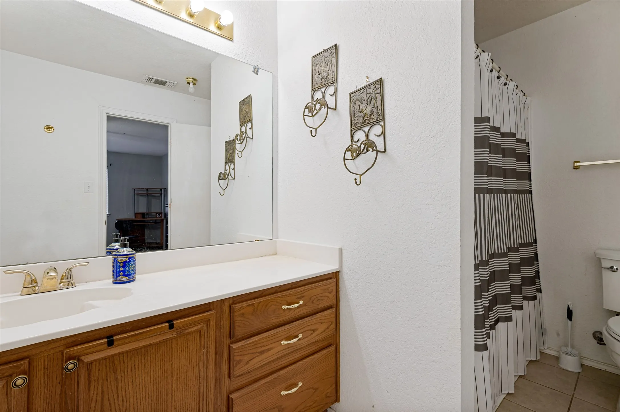 Vanity with a light-toned countertop, wood-finish cabinetry, and an integrated basin