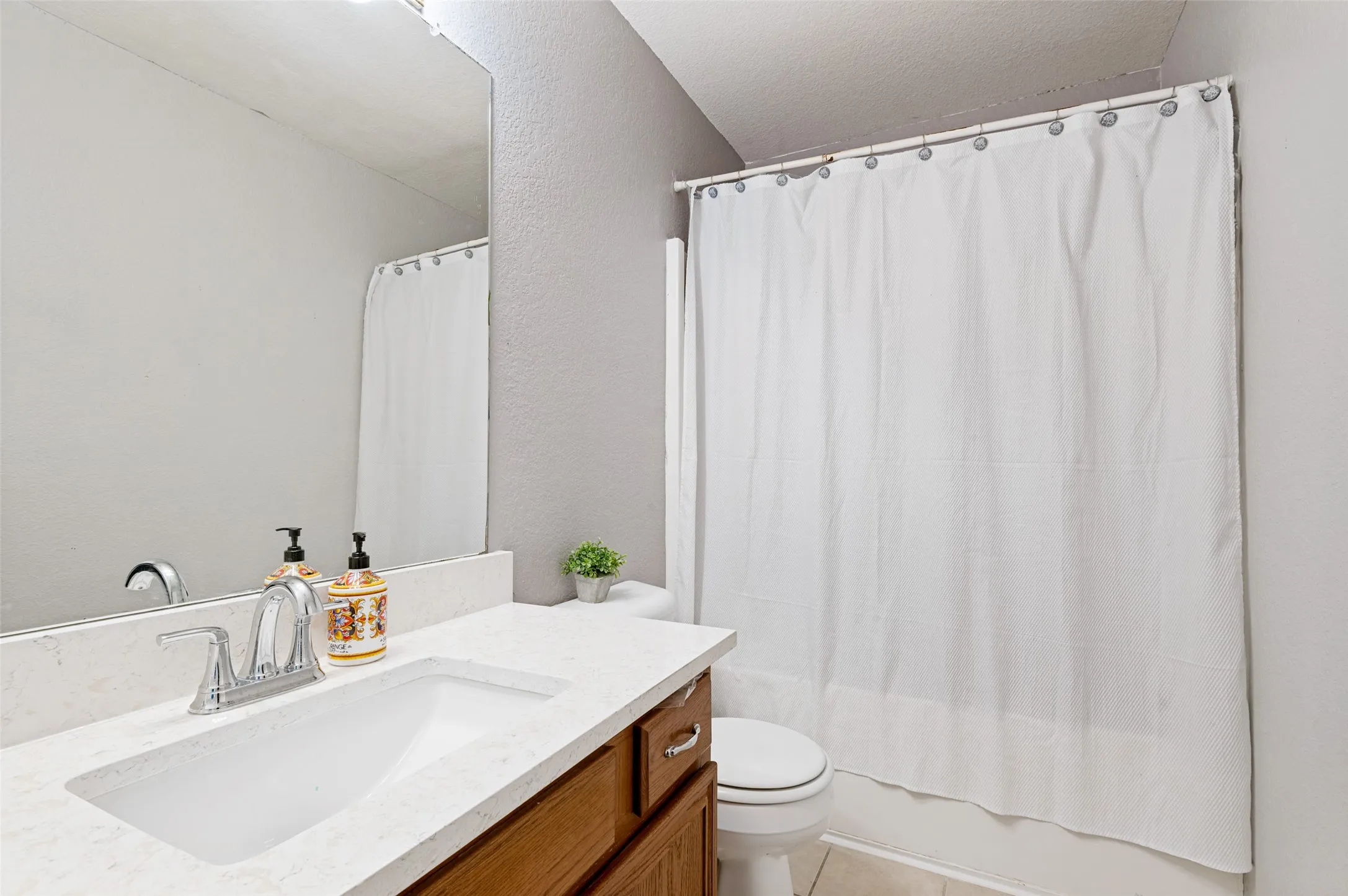 Bathroom featuring a single vanity with an integrated sink, chrome faucet, and wood-finish cabinetry