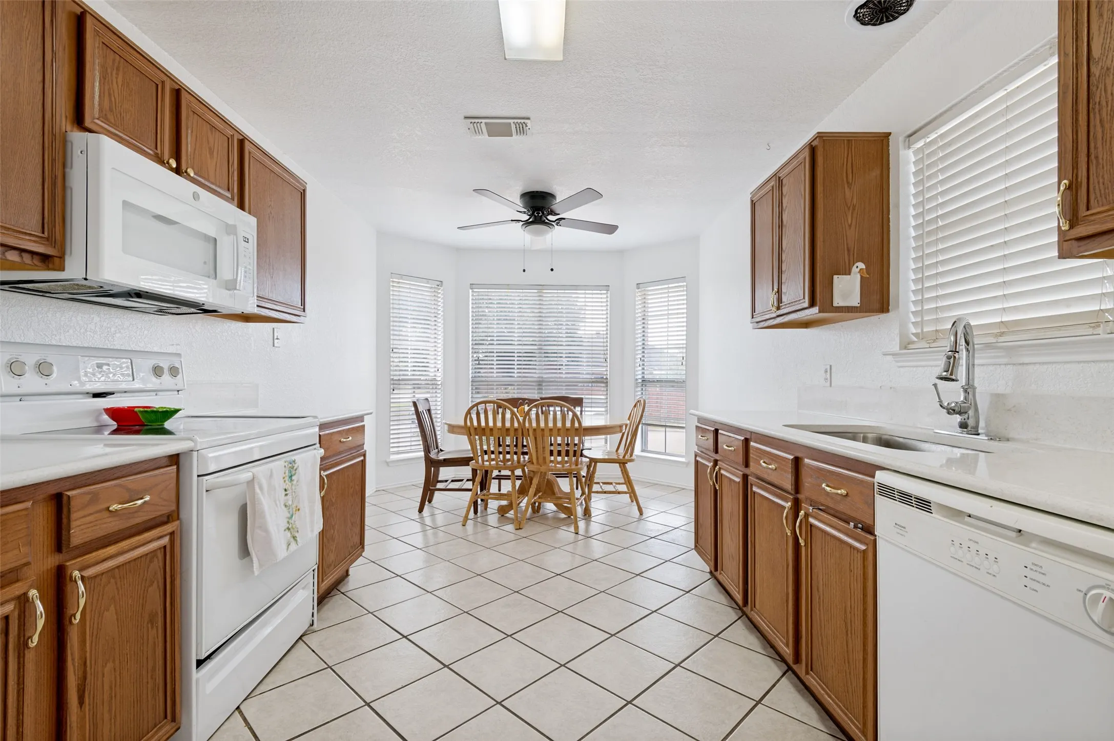Kitchen with wood-finish cabinetry, white countertops, a built-in microwave, and a white electric range