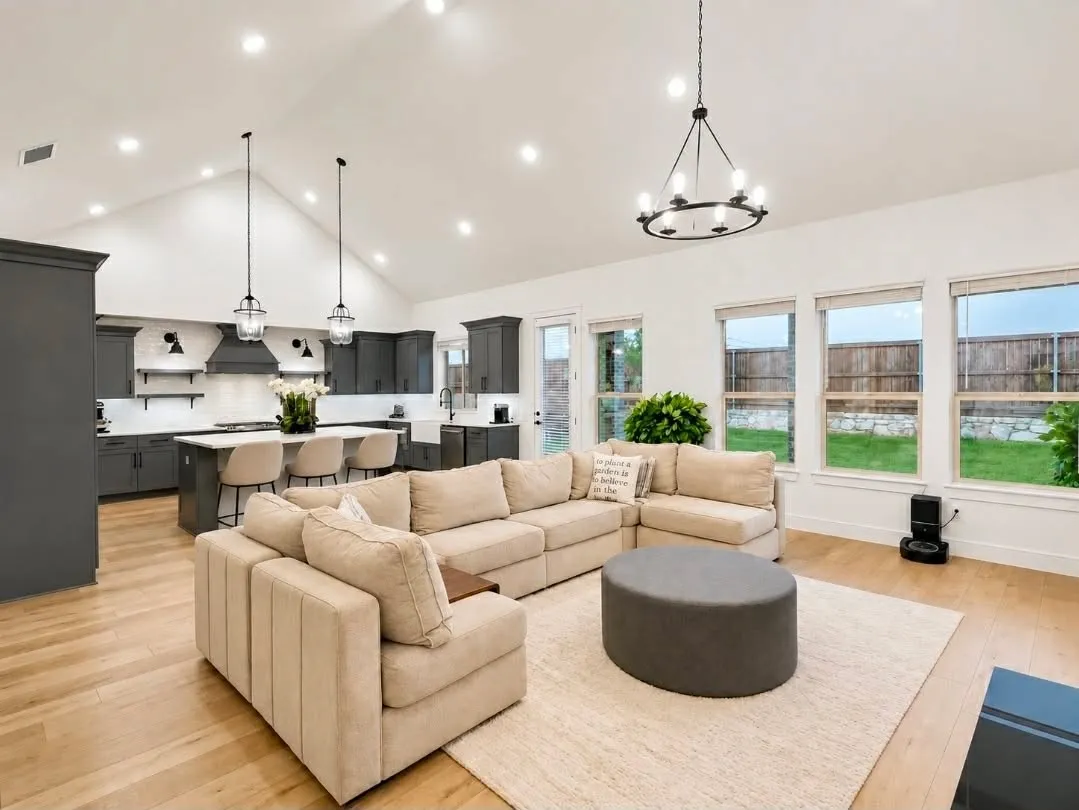 Open-concept living space featuring vaulted ceilings, wood-finish flooring, a contemporary chandelier, and recessed lighting