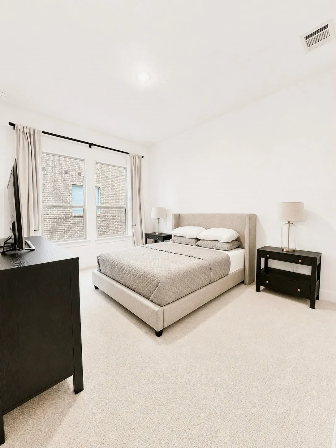 Light-colored carpeting complementing white walls, featuring a window with dark hardware, and a ceiling-mounted light fixture