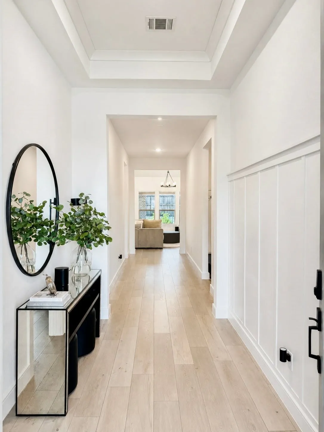 Entryway featuring light wood-finish flooring, white board and batten wall detailing, and a tray ceiling