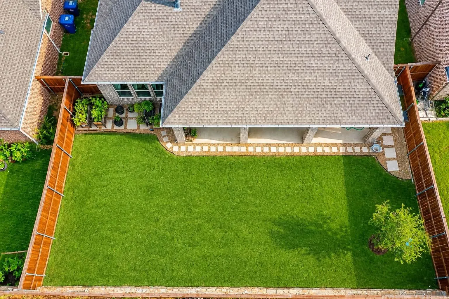 Spacious backyard featuring a manicured lawn, a covered patio, and a privacy fence