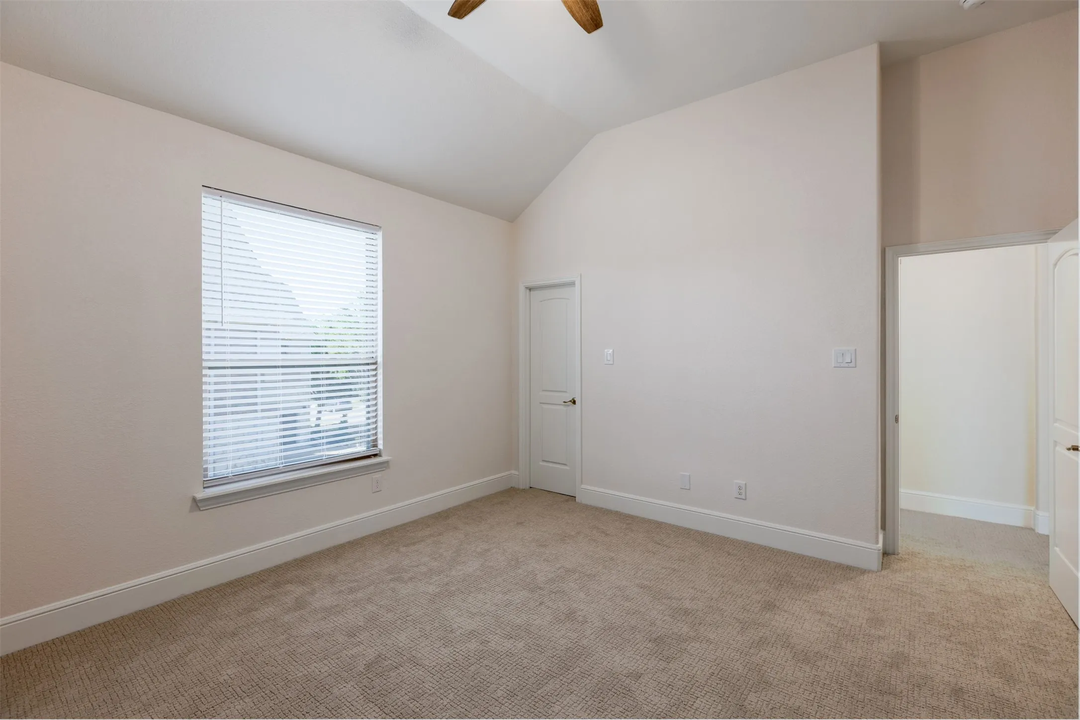 Bedroom with a ceiling fan, vaulted ceiling, and light colored carpet