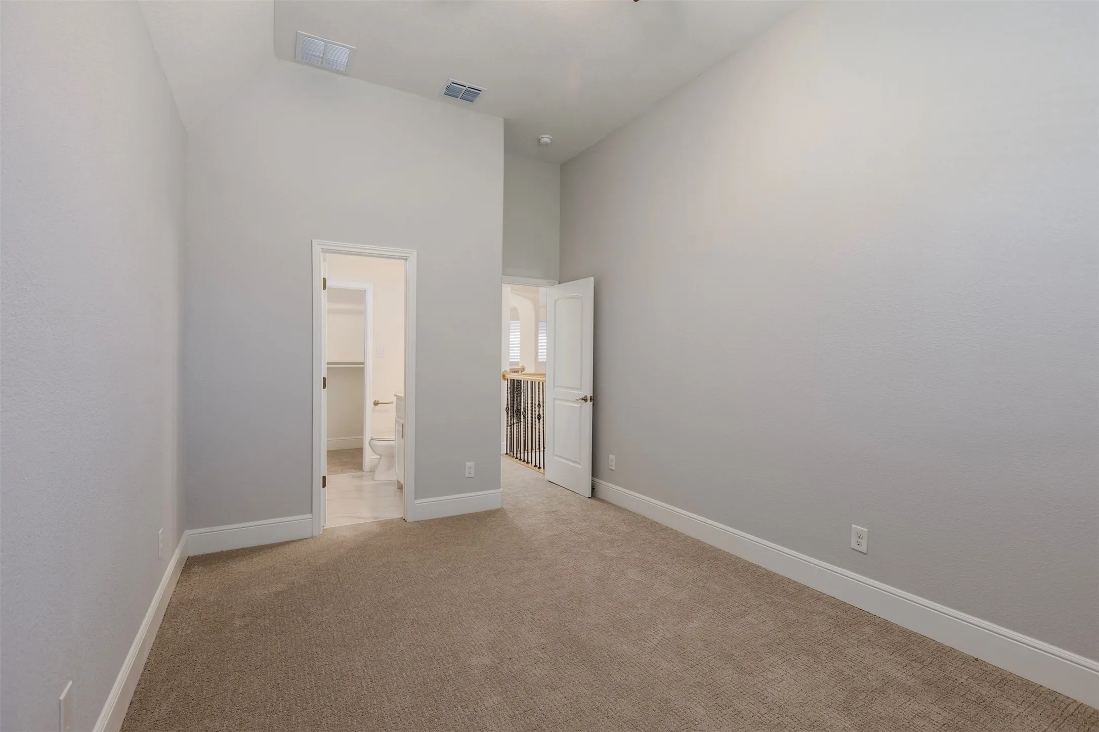 Bedroom featuring light colored carpet, lofted ceiling, and connected bathroom