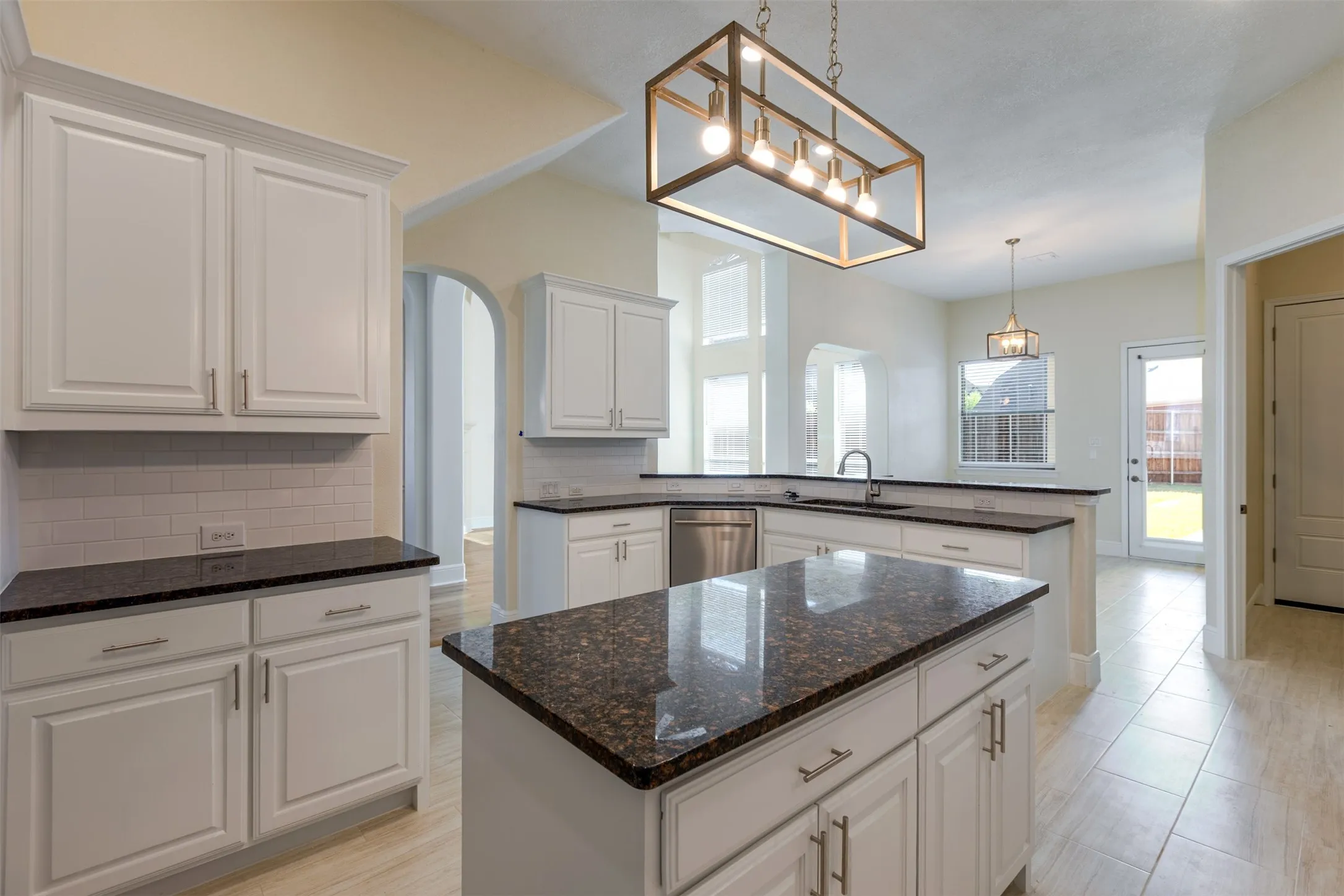 Kitchen with a peninsula, white cabinets, decorative backsplash, a center island, and healthy amount of natural light