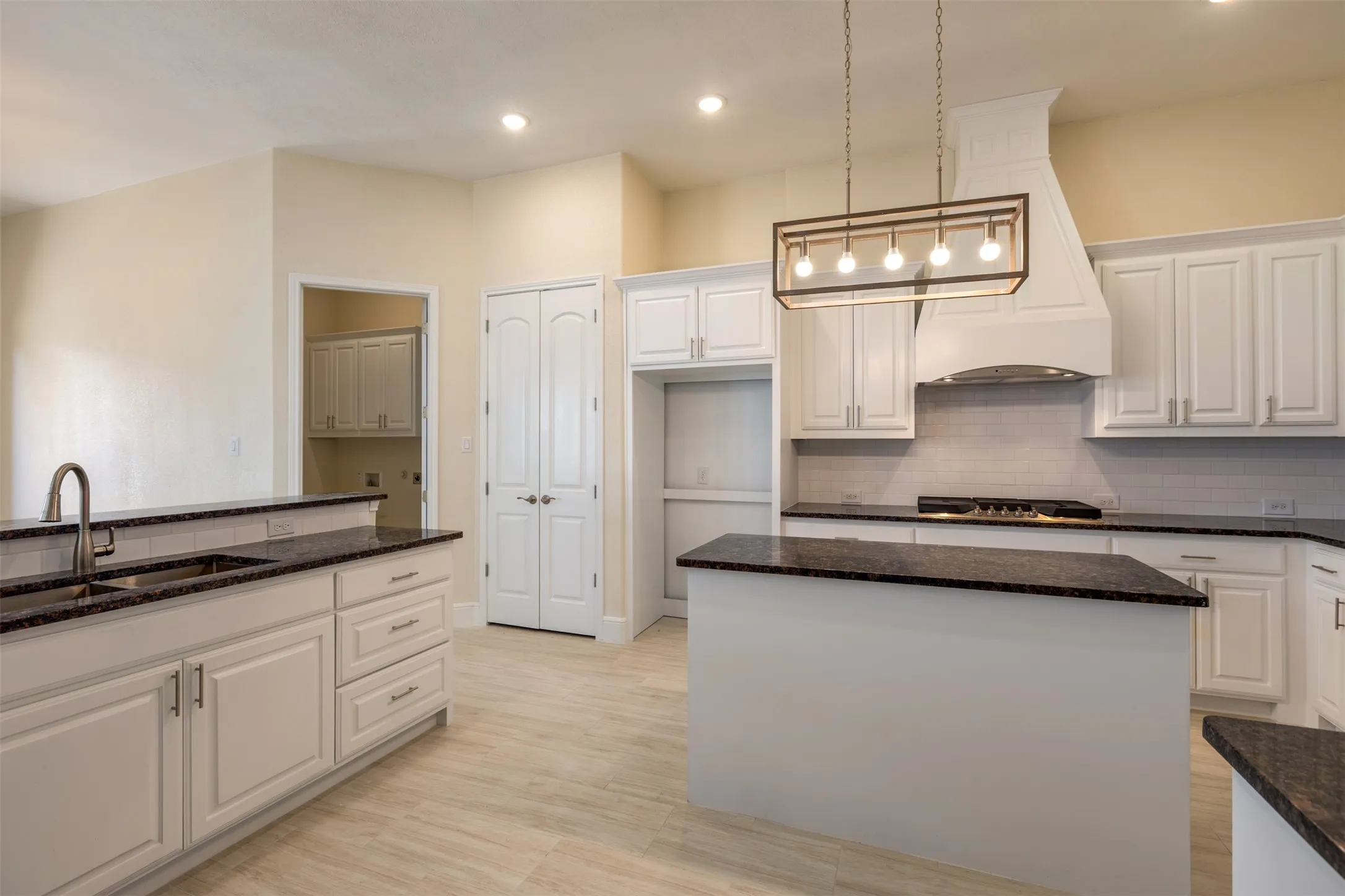 Kitchen with dark stone countertops, white cabinets, a center island, decorative light fixtures, and decorative backsplash
