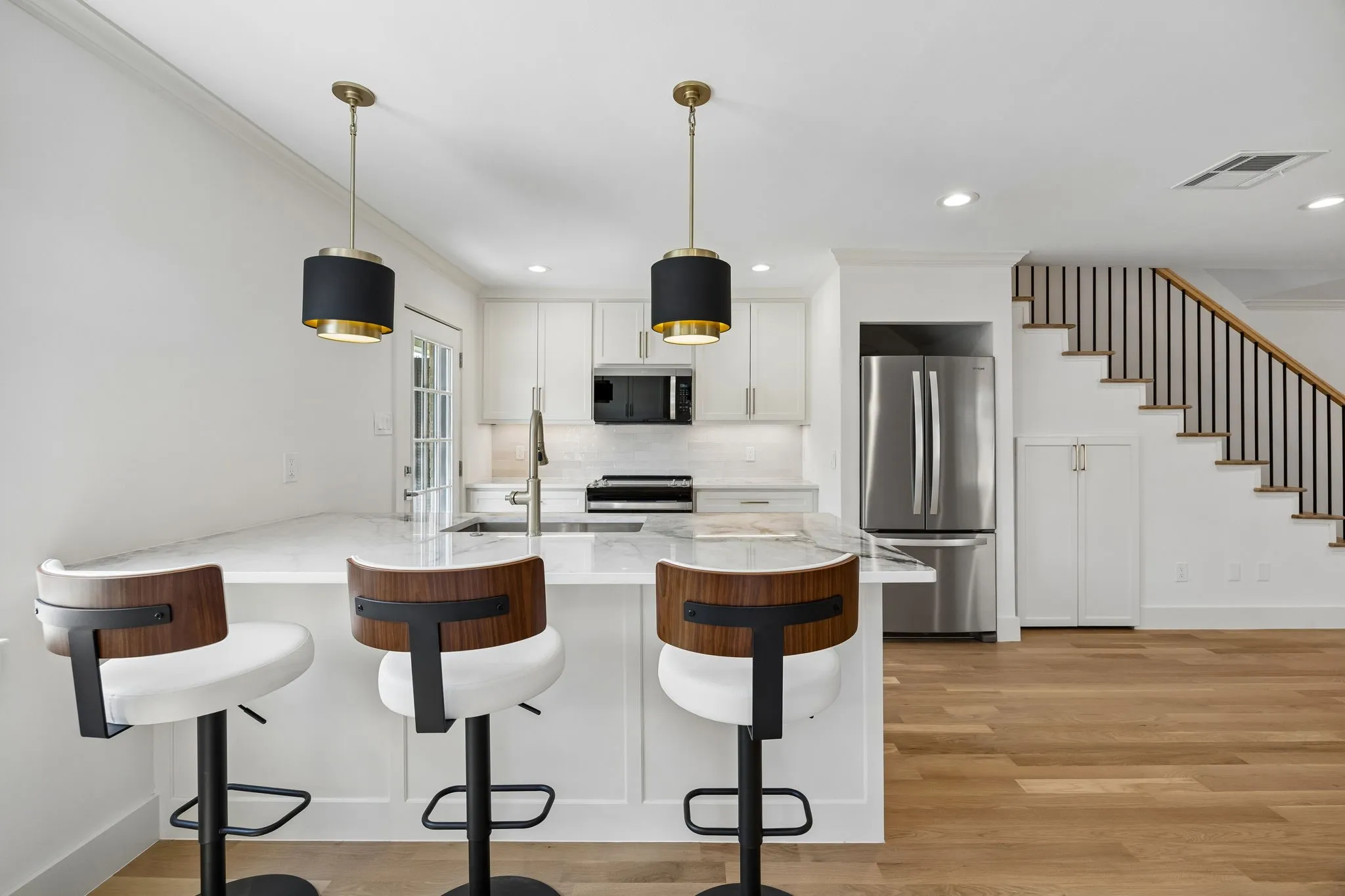 Open-concept kitchen featuring an island with stone countertops, stainless steel appliances, and white cabinetry