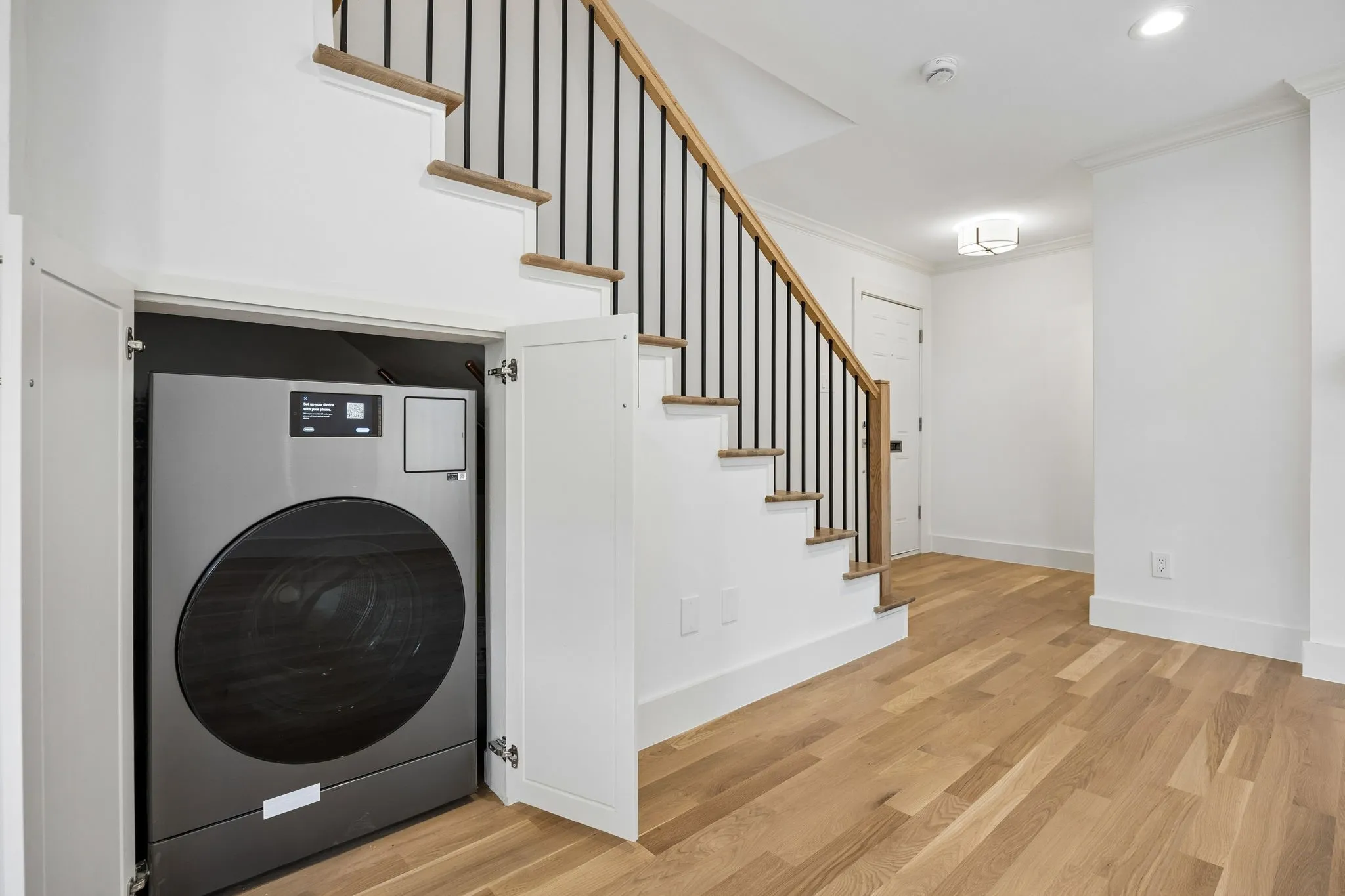 Integrated under-stair laundry appliance concealed by white cabinetry