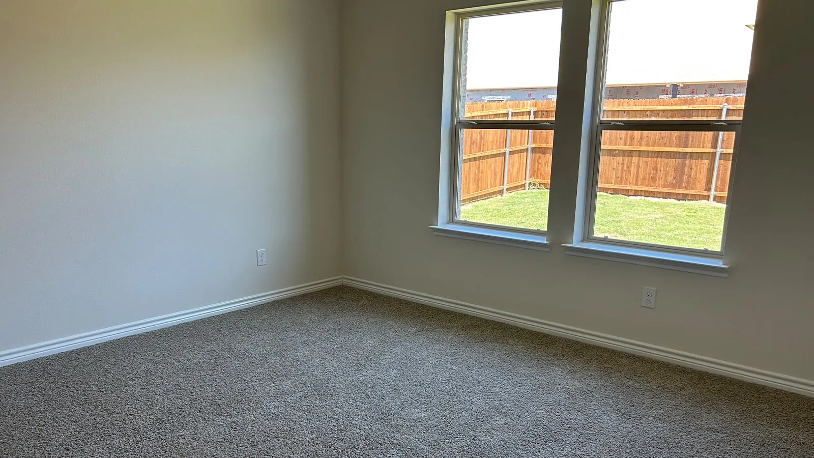 Neutral wall paint, plush carpet flooring, multiple windows, and a private fenced yard