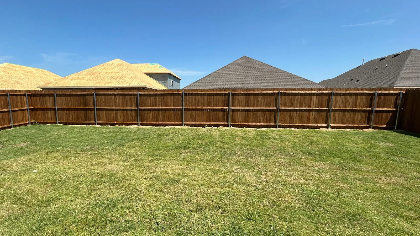 Expansive backyard featuring a manicured lawn and a durable wood privacy fence