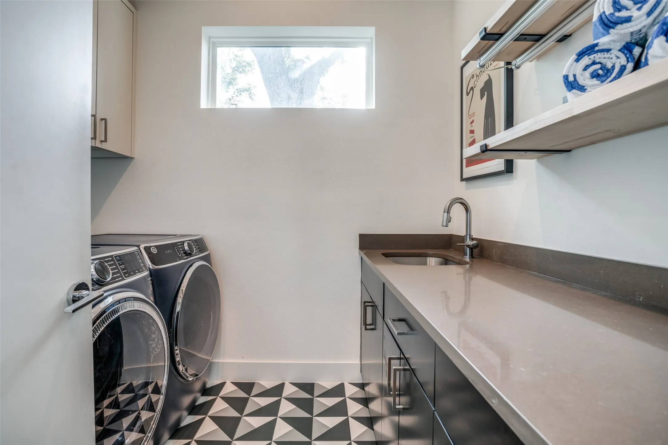 Washroom featuring space for independent full sized washer and dryer, plenty of cabinet space, quartz countertop folding area, a window for natural light and tile patterned floors.