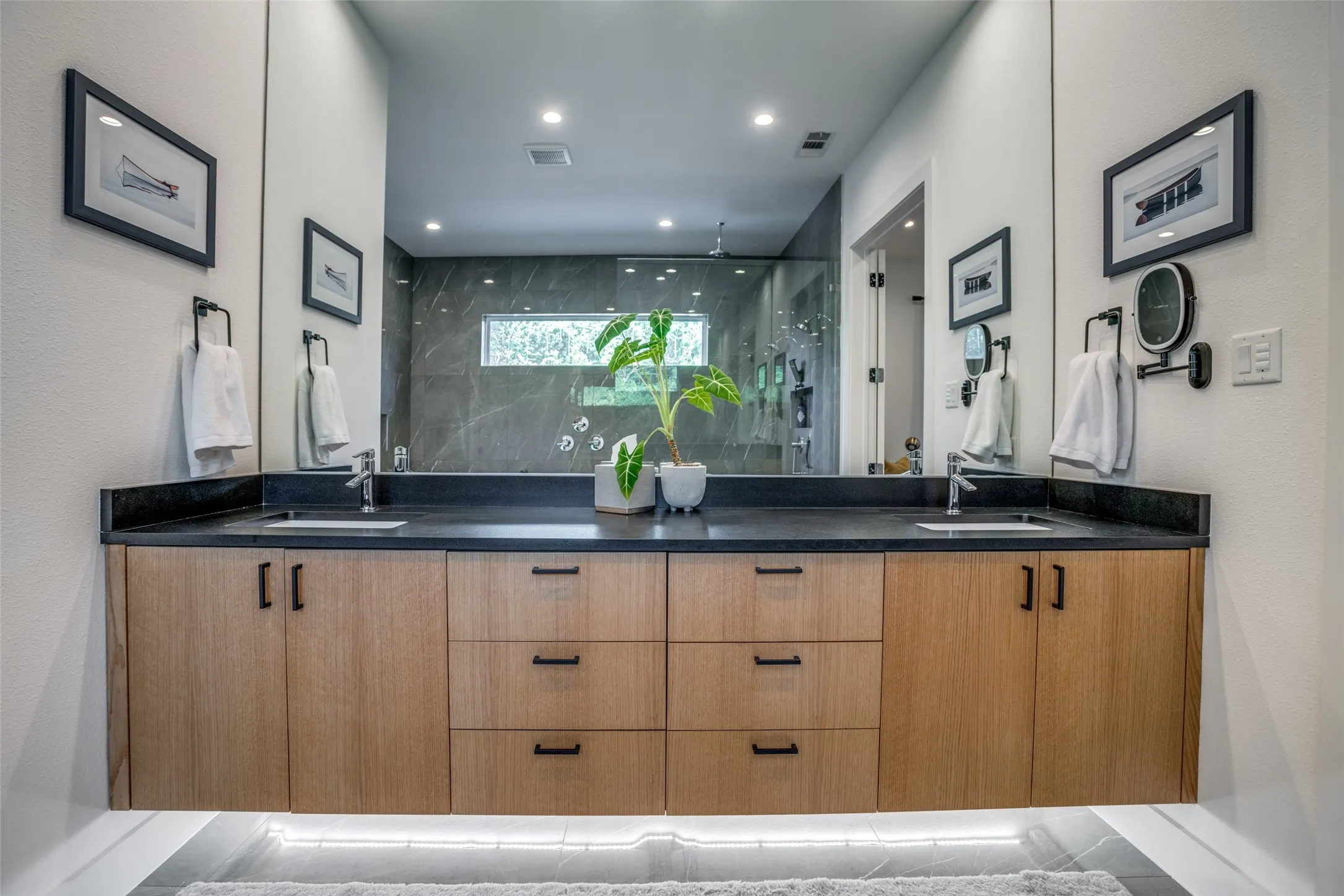 Quartz counter floating vanity has under cabinet lighting and double under mounted sink.