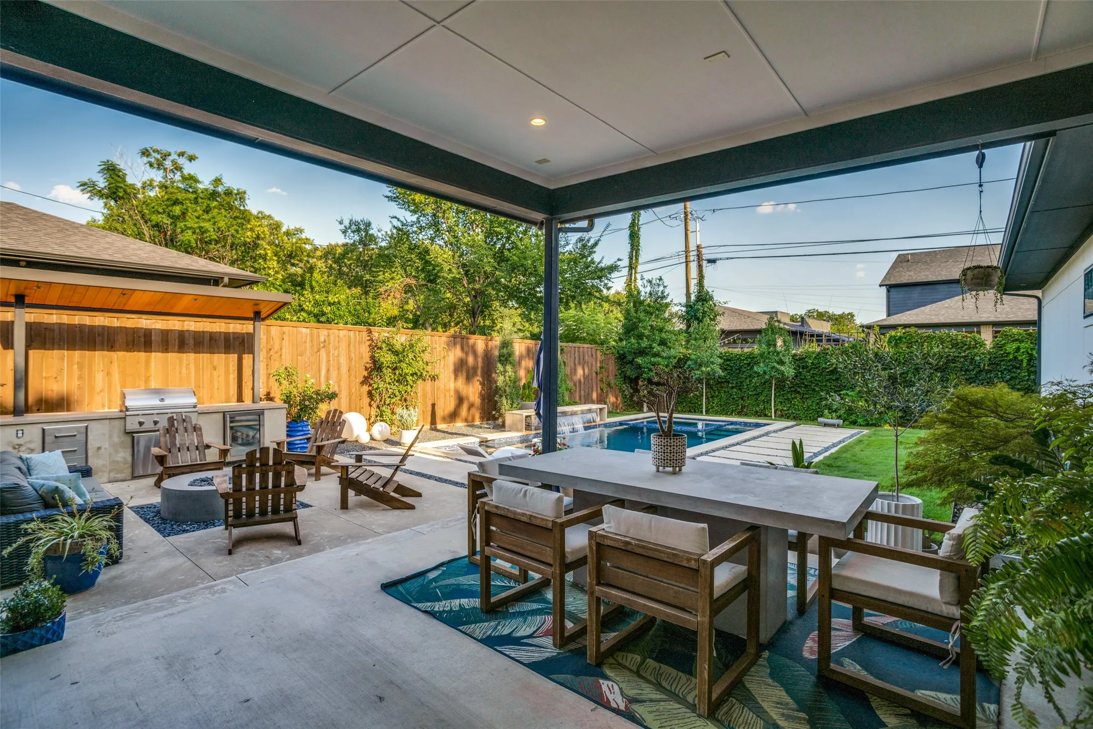 8' board on board fenced backyard with outdoor dining area, an outdoor living space with a fire pit, a patio area, and area for grilling and gorgeous salt water pool/spa.