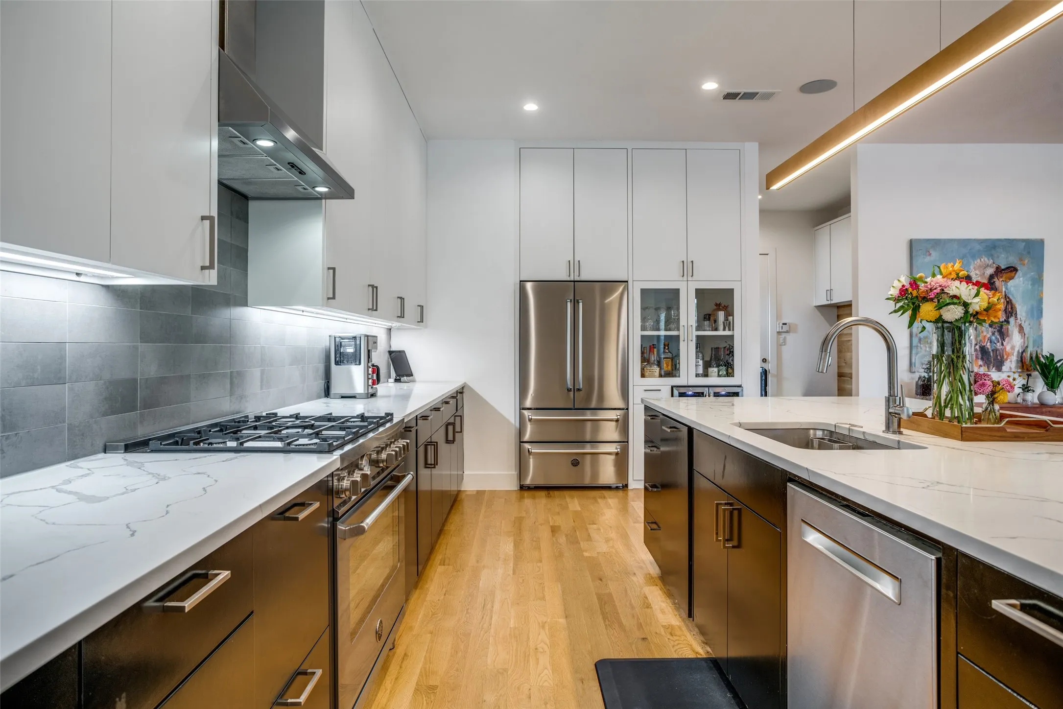 Kitchen with white upper cabinets and black lower cabinets, premium Bertazzonni 36" French door dual freezer drawer refrigerator, 24" Danby French door wine fridge. Kitchen Connectes to a convenient mudroom that leads to the garage and a large walk in pantry.