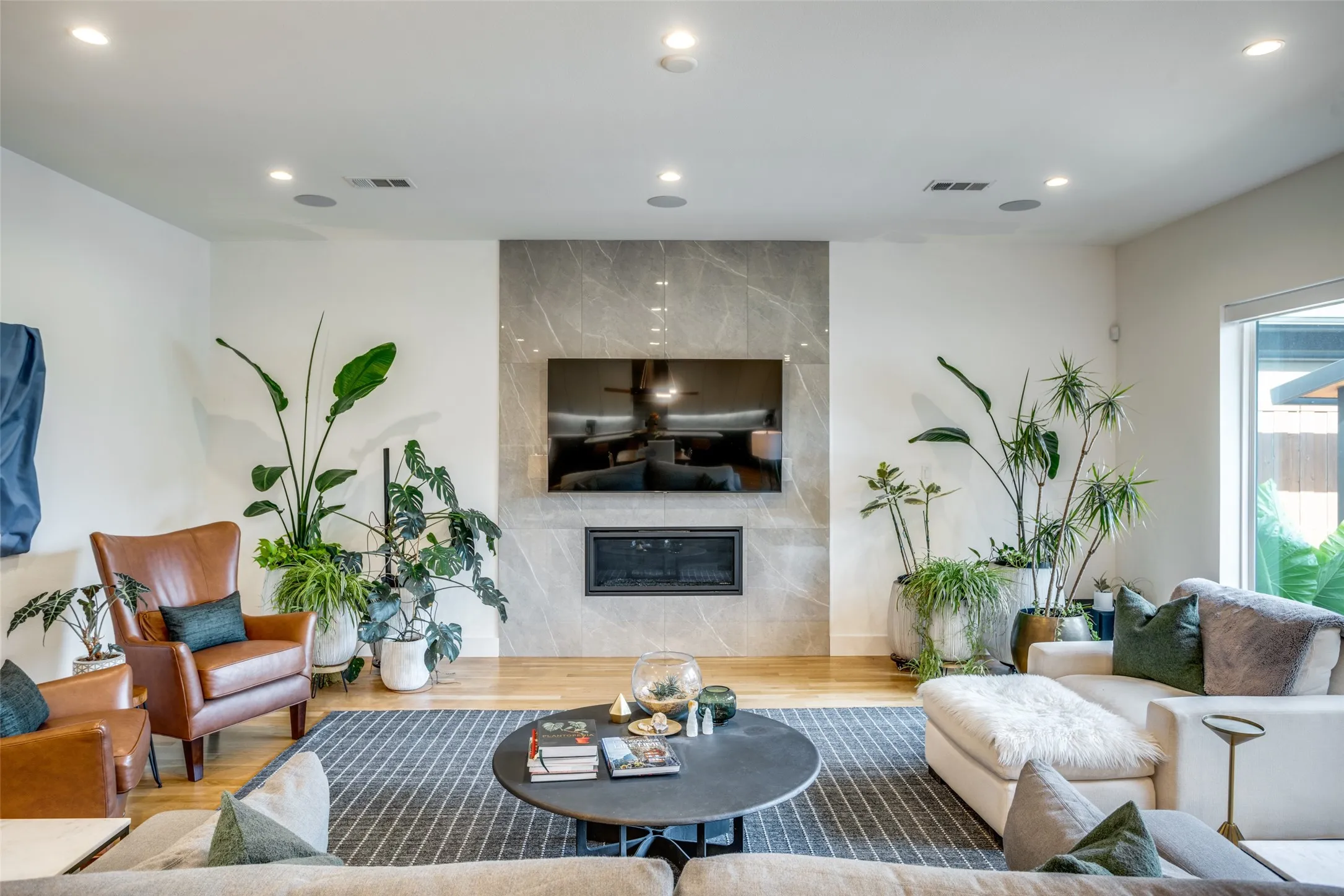 Living room featuring surround sound, wood finished floors, and a premium floor to ceiling ELEGANZA tiled auto ignite fireplace. surround sound and recessed lighting can be controlled by the smart panel.