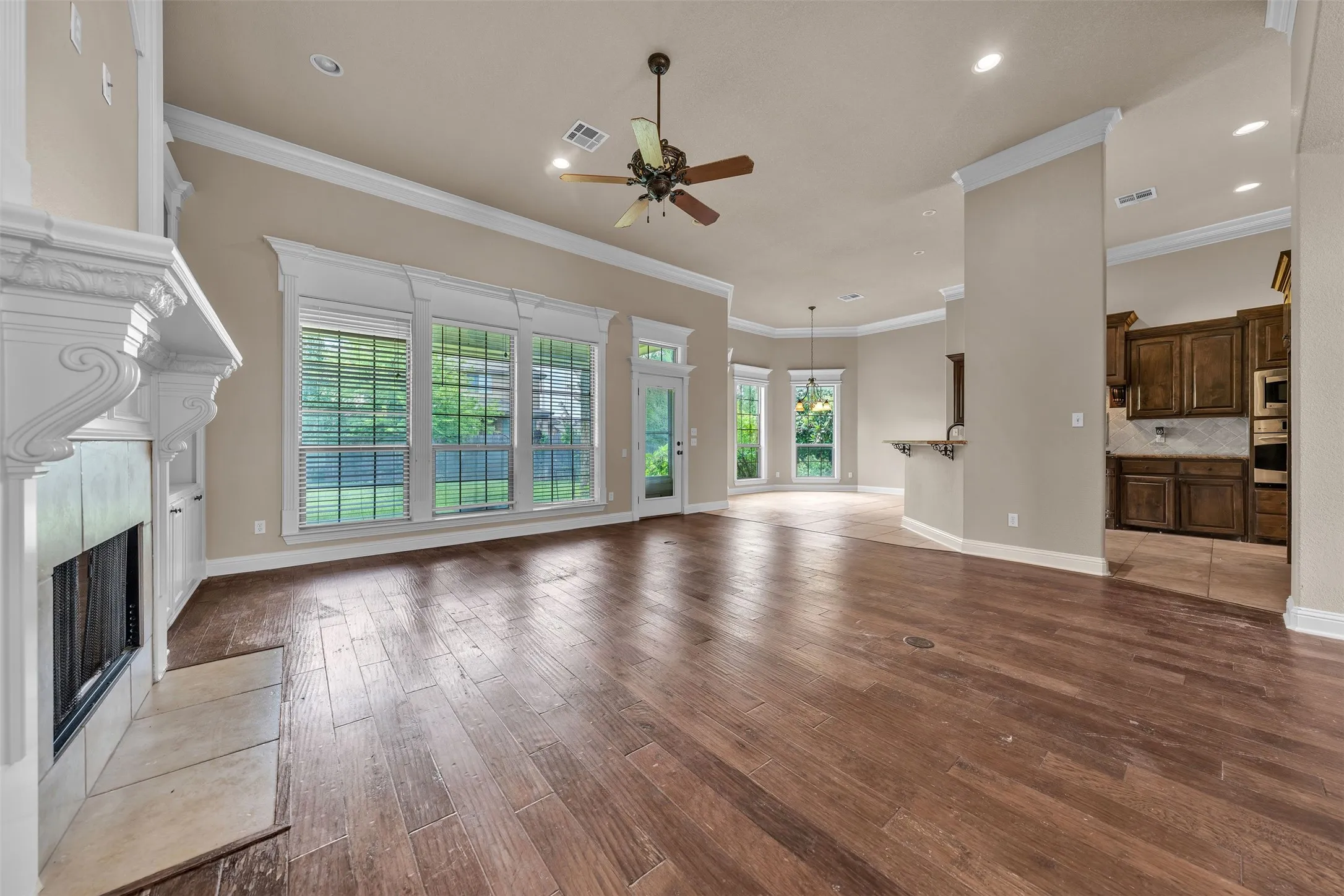 Expansive living area featuring wood-finish flooring, a decorative fireplace with a tile hearth, and built-in cabinetry