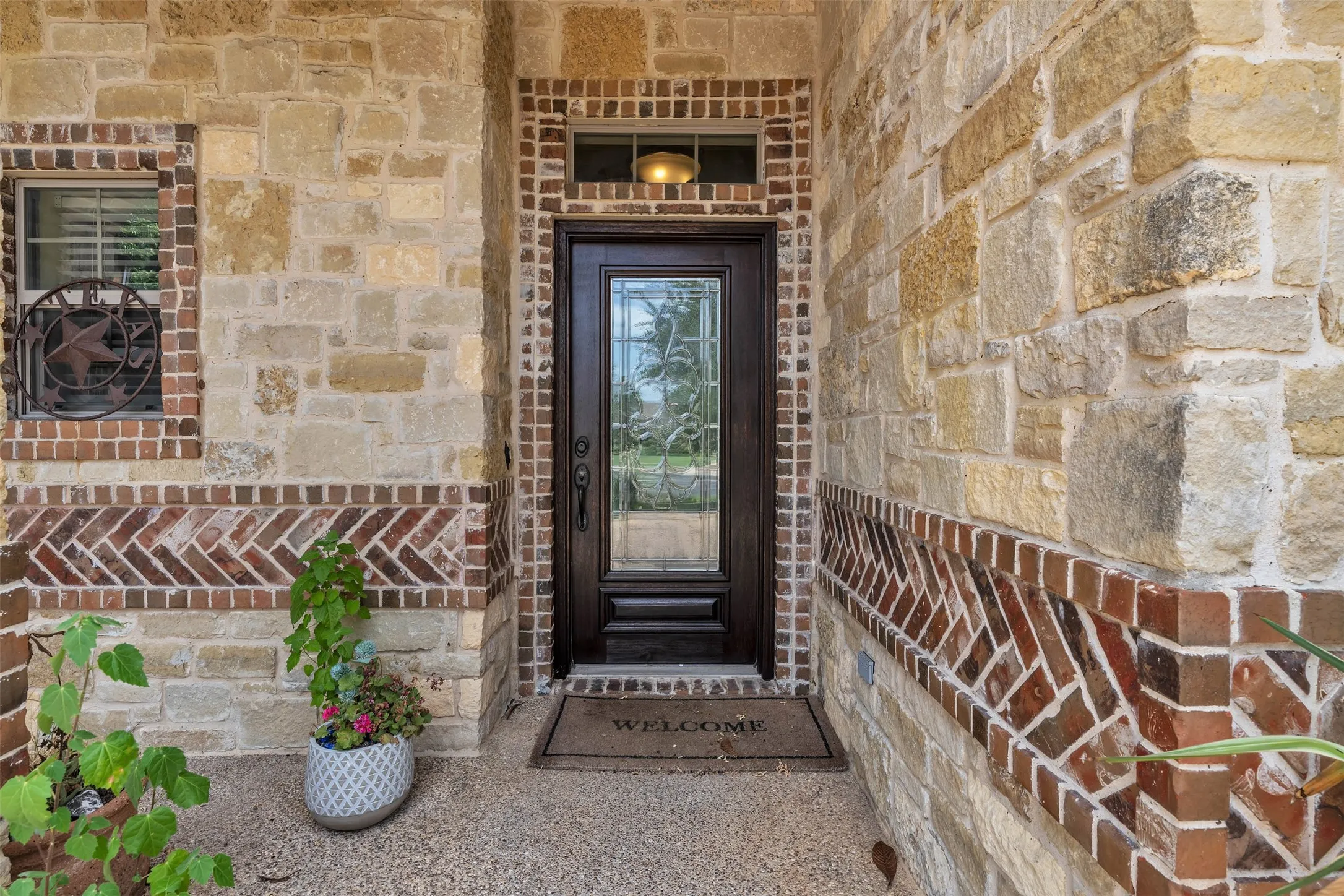 Stone and brick facade featuring a dark wood-finish entry door with leaded glass
