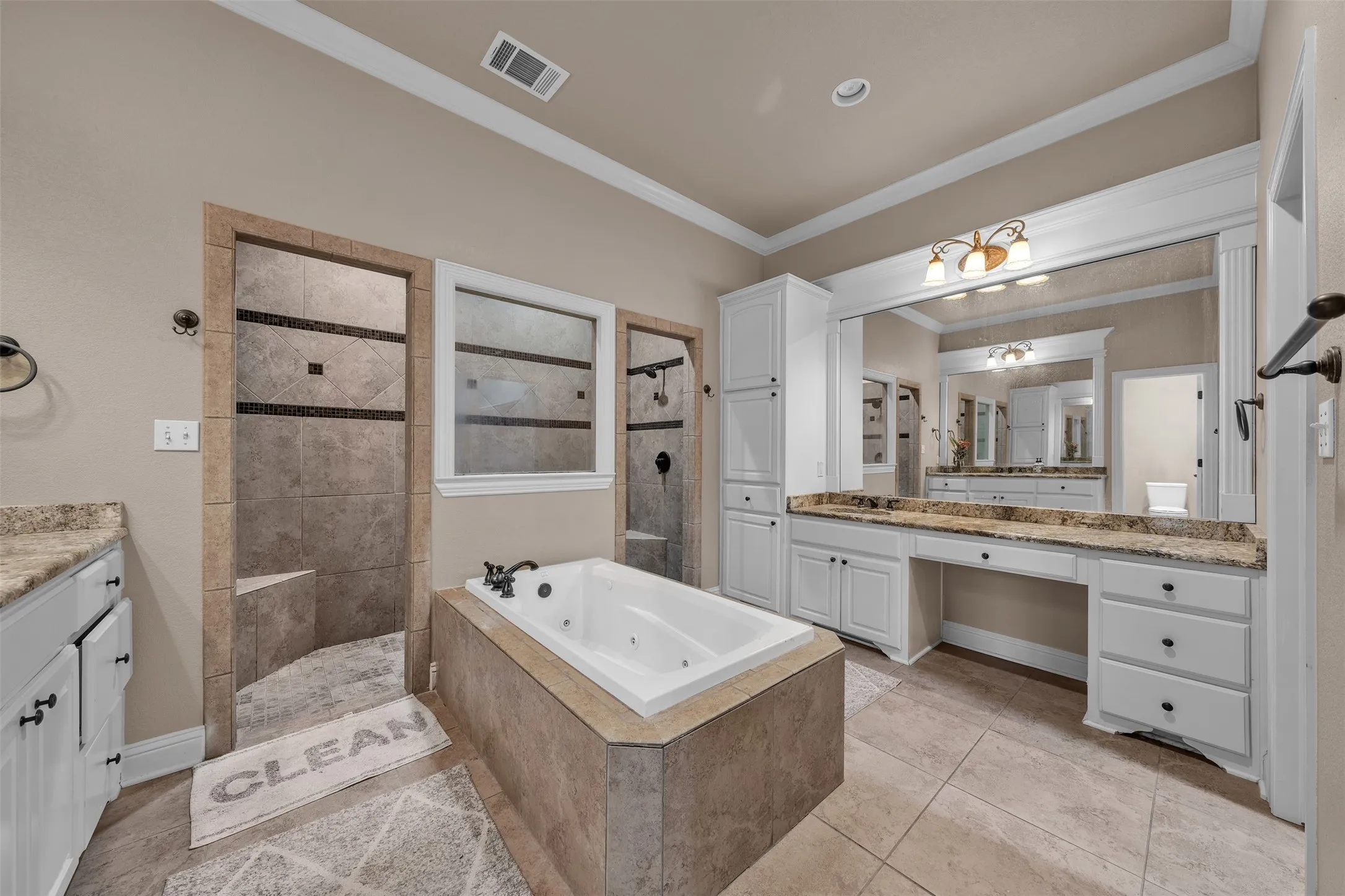Expansive bathroom featuring a jetted soaking tub, twin walk-in showers with tile surround, a dual vanity with stone-finish countertops, and white cabinetry