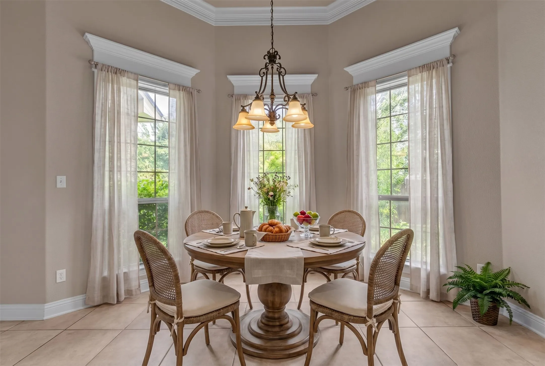 Elegant dining area featuring a tiered chandelier, crown molding, and large windows with transom detailing