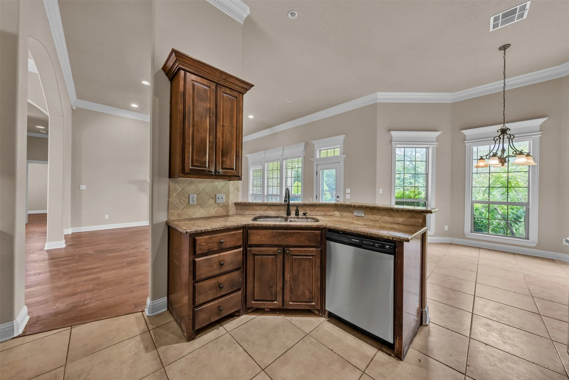 Corner kitchen counter featuring dark wood cabinetry, a built-in stainless steel dishwasher, and a sink with a matte black faucet