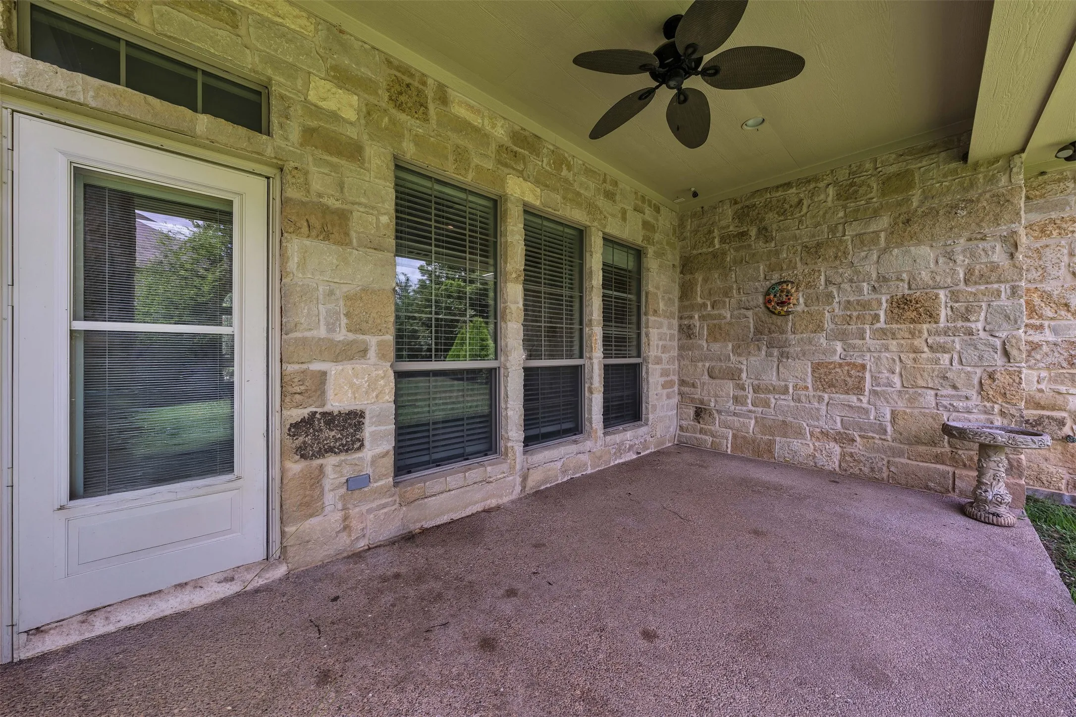 Covered patio featuring a ceiling fan, recessed lighting, and a stone-clad exterior wall