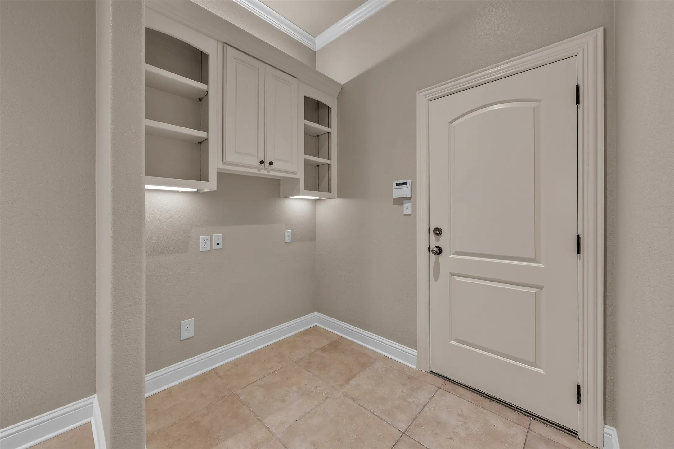 Built-in cabinetry with task lighting, wall shelving, paneled interior door, and tiled flooring