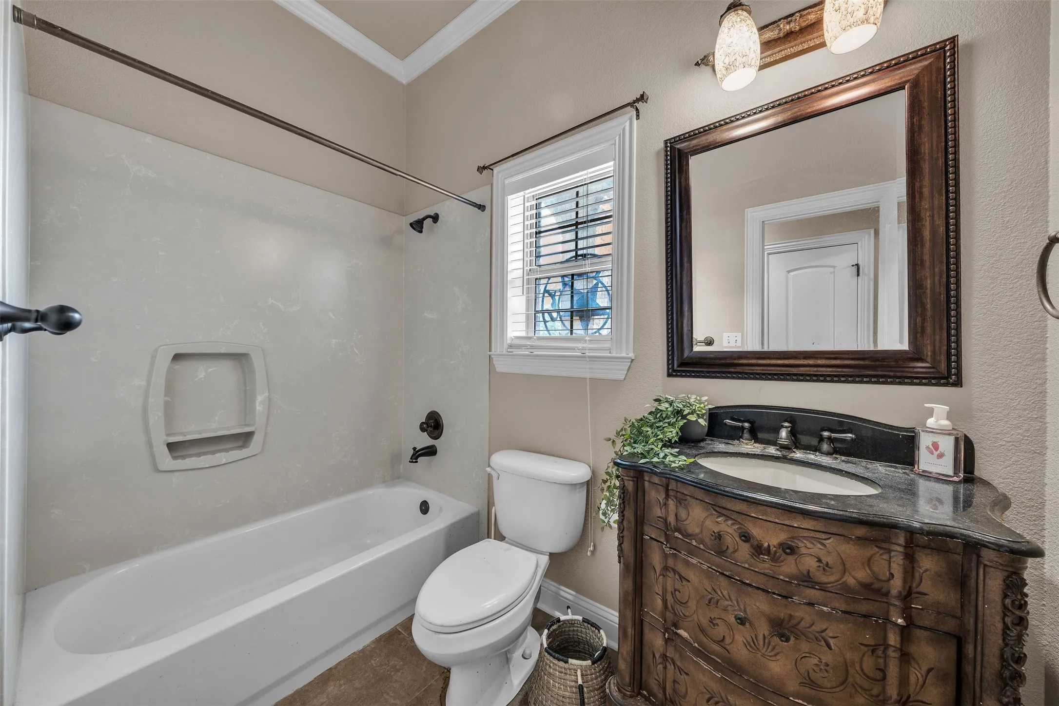 Bathroom featuring a decorative vanity with an integrated sink, framed mirror, and a window with blinds